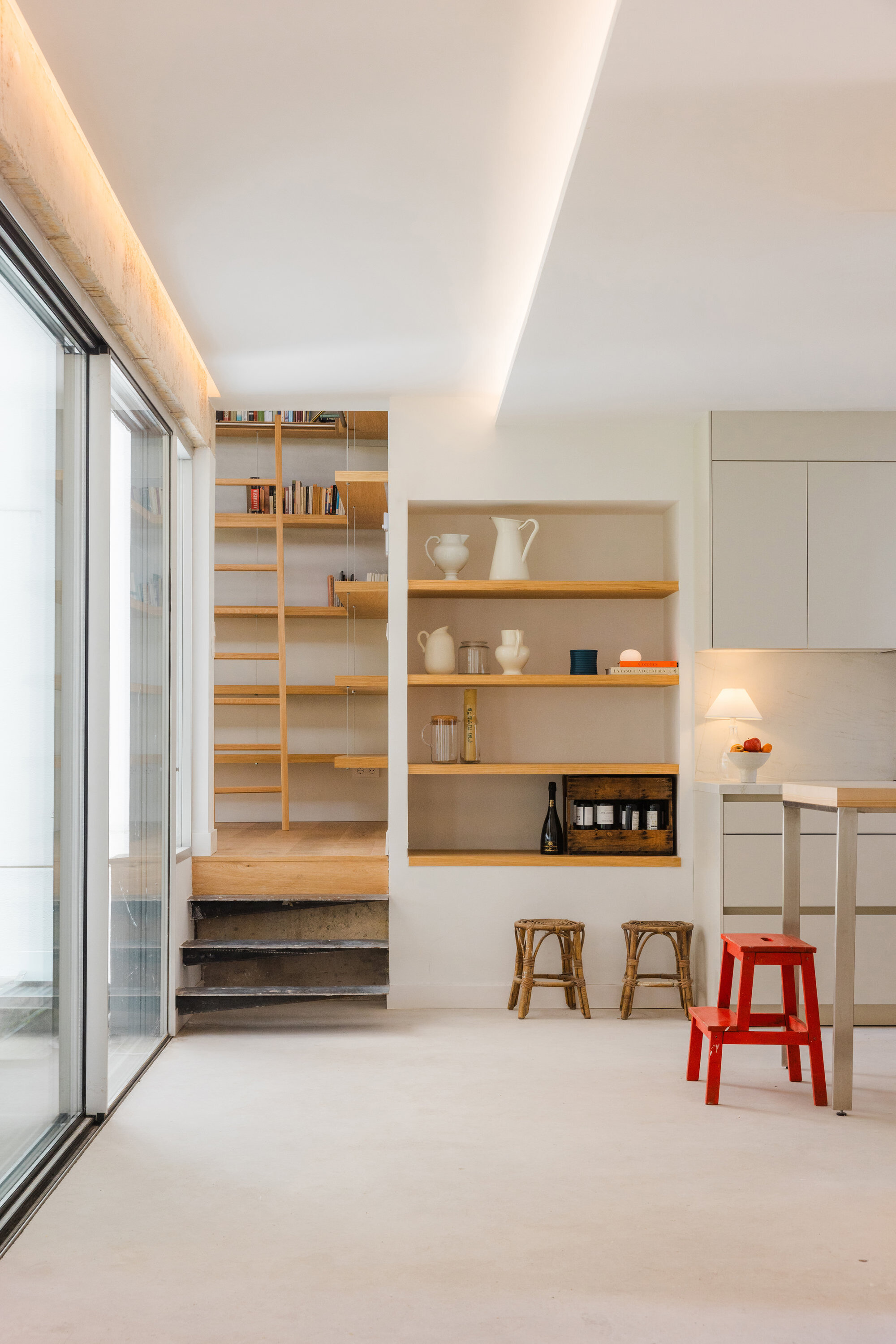 Kitchen area with timber open shelving and raised platform steps under coved ceiling lighting