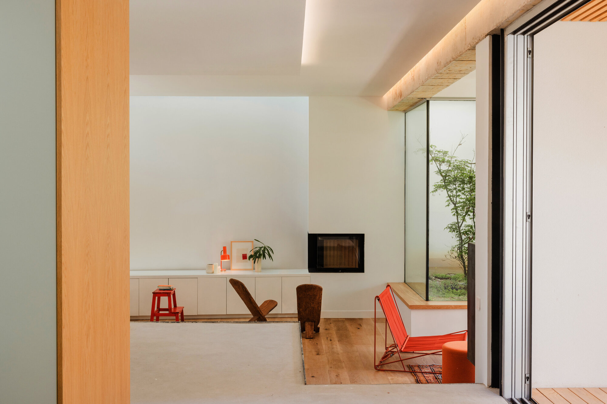 View through sliding doors to living area with inset fireplace and glazed courtyard beyond