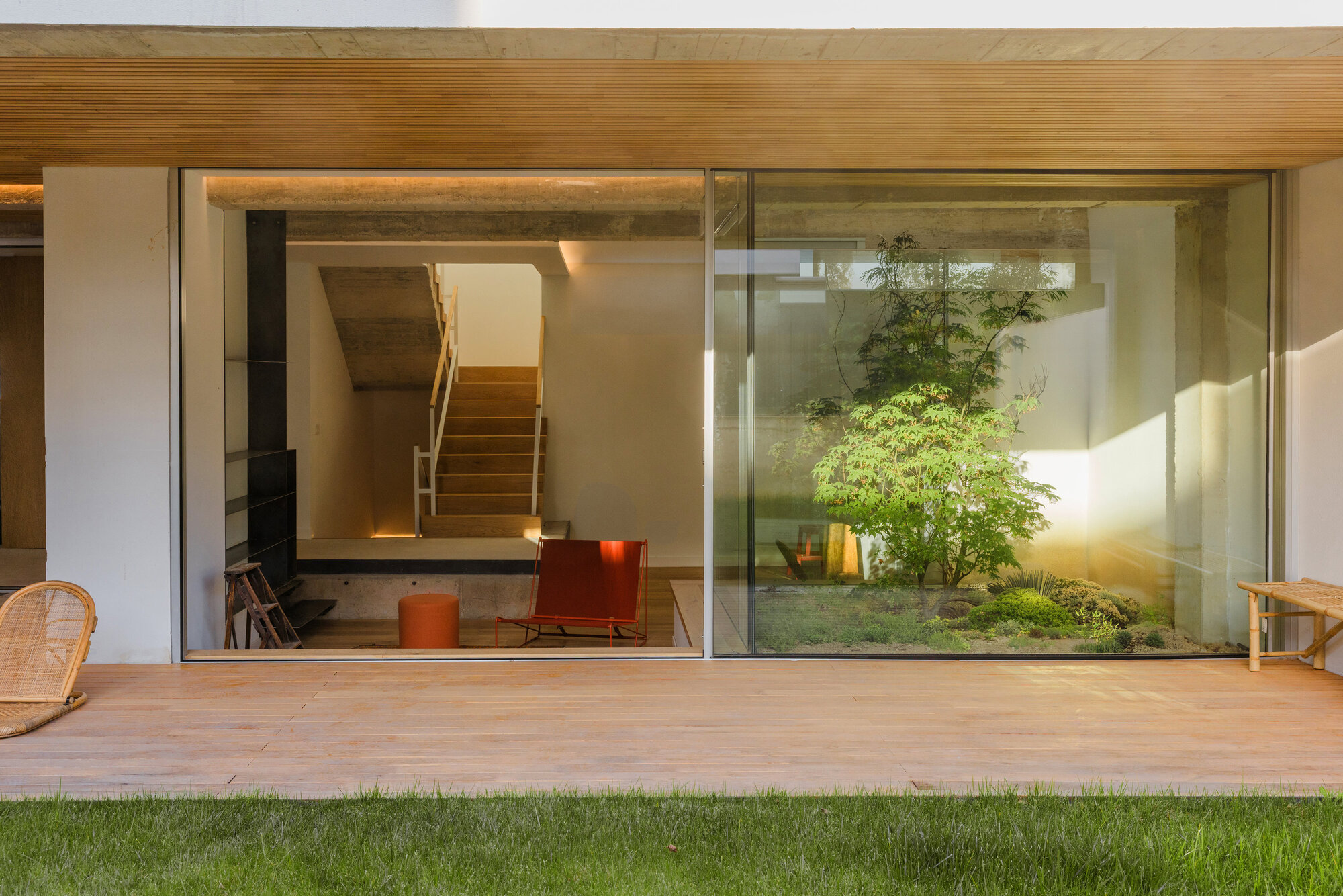 Timber-framed opening with sliding glass doors looking into a living space and internal courtyard with greenery