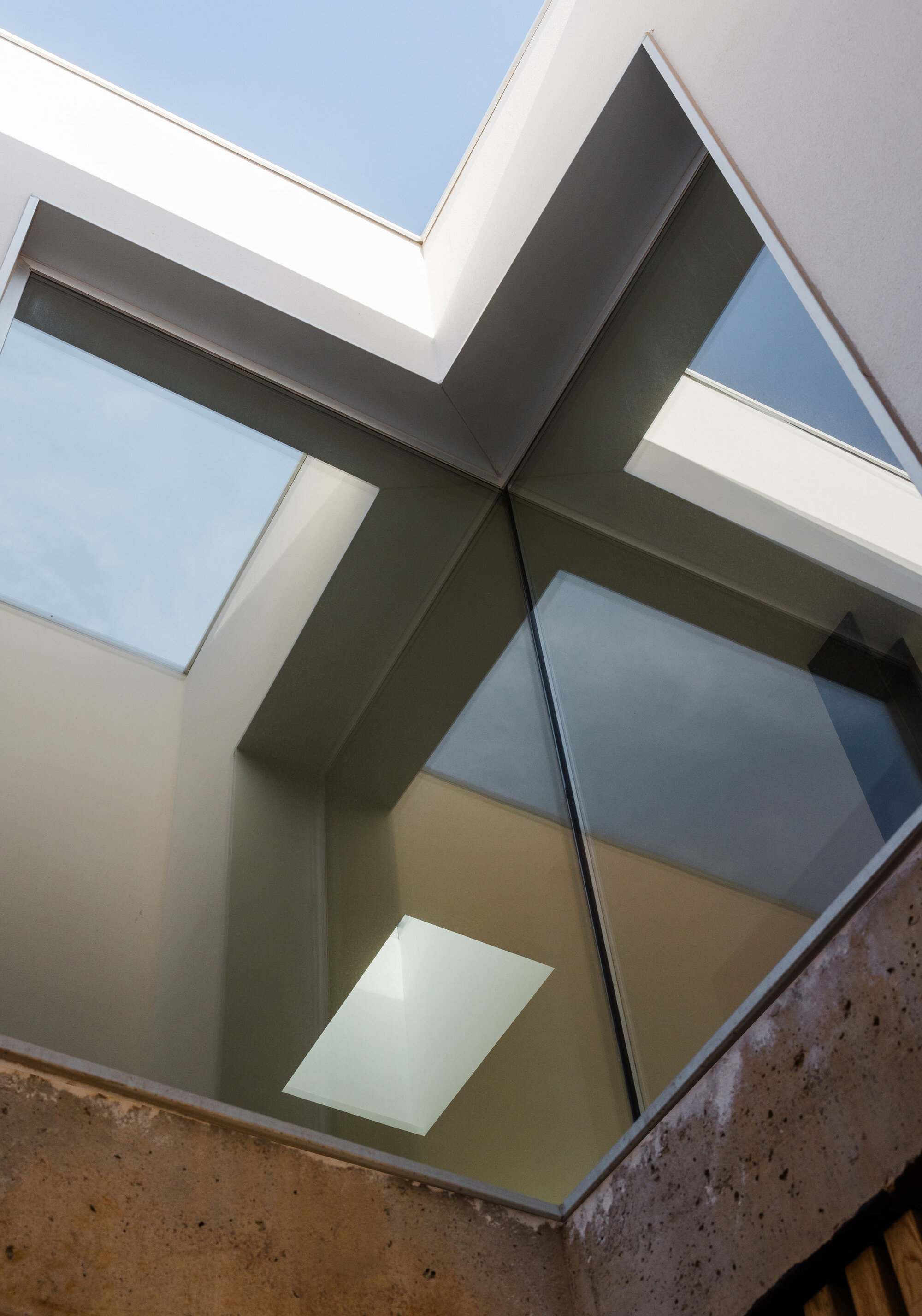 Upward view of glazed courtyard roof with crossing steel beams forming an X shape