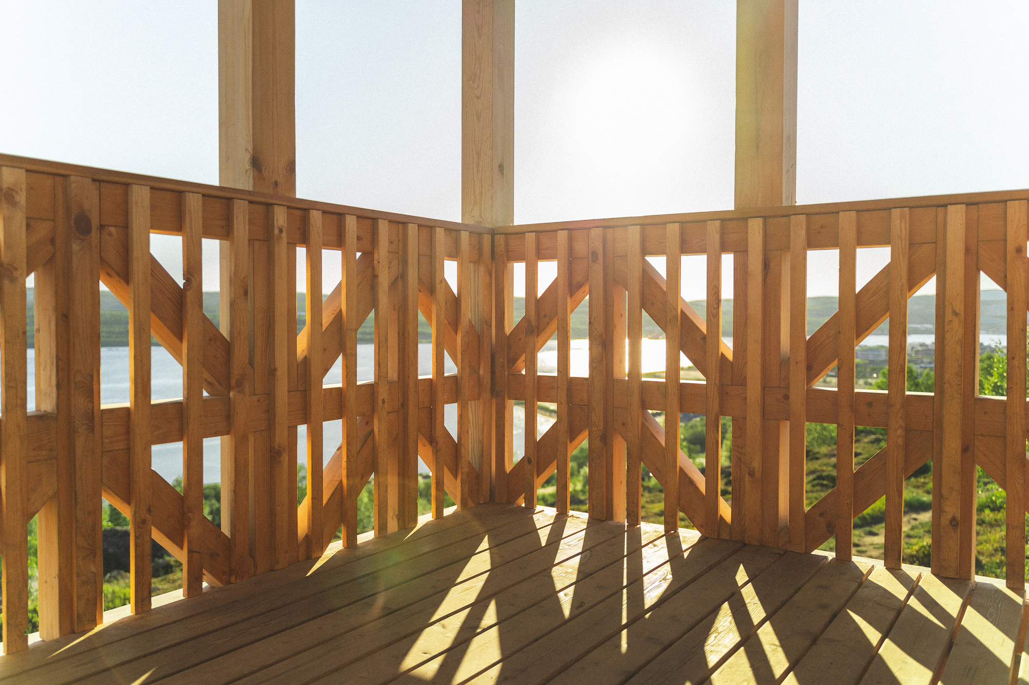Geometric timber screen casting shadows on the deck floor with valley views beyond
