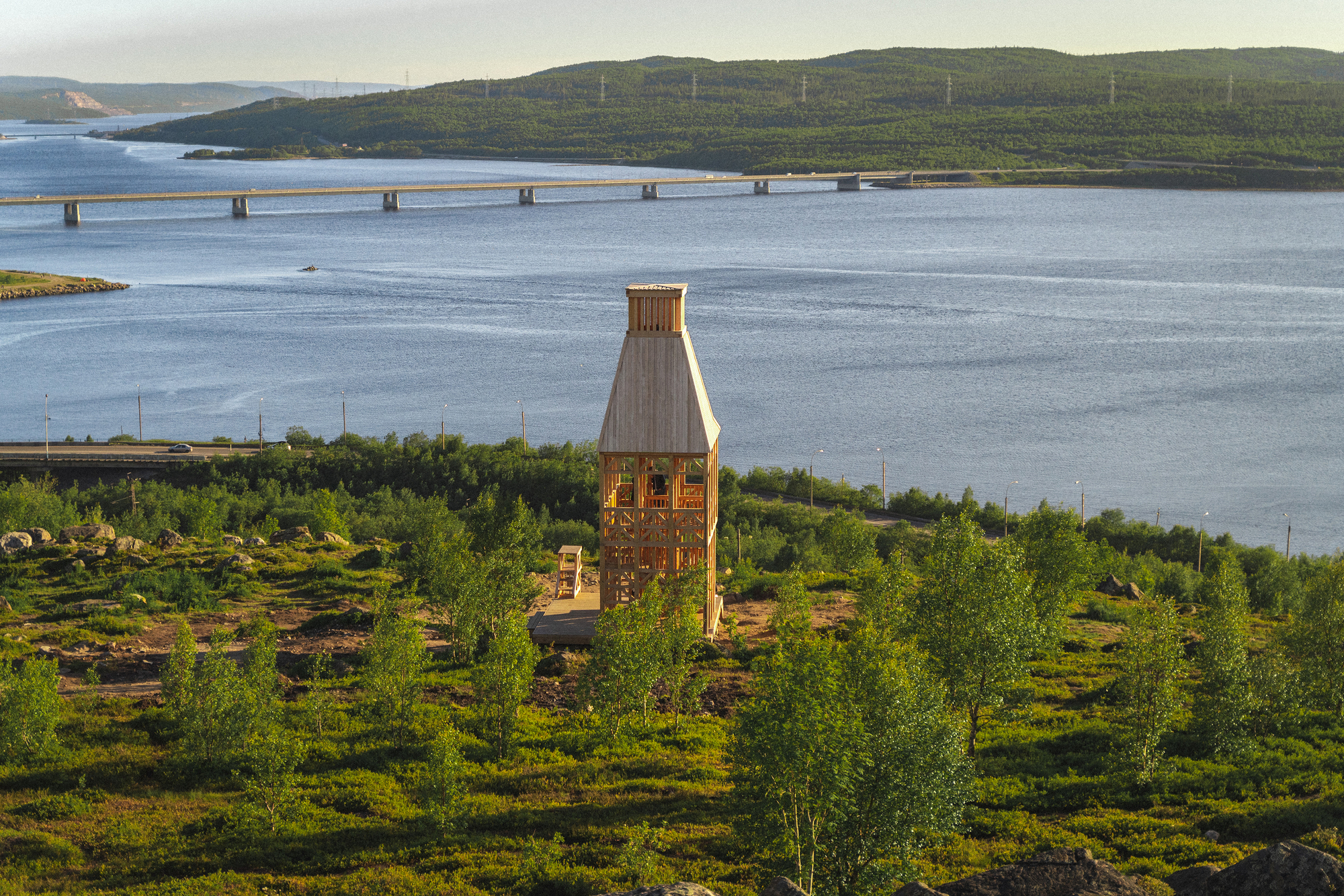 The tower and adjacent low building on a hillside above the water with bridge beyond