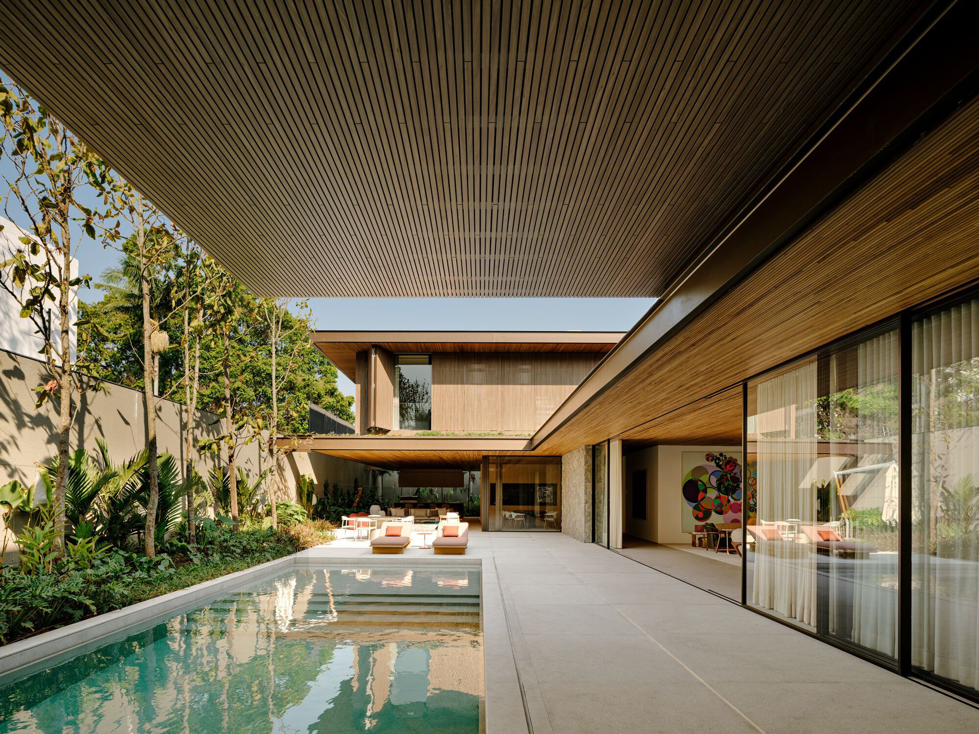 Covered poolside terrace with timber-slatted soffit and clerestory skylight framing the courtyard in daylight