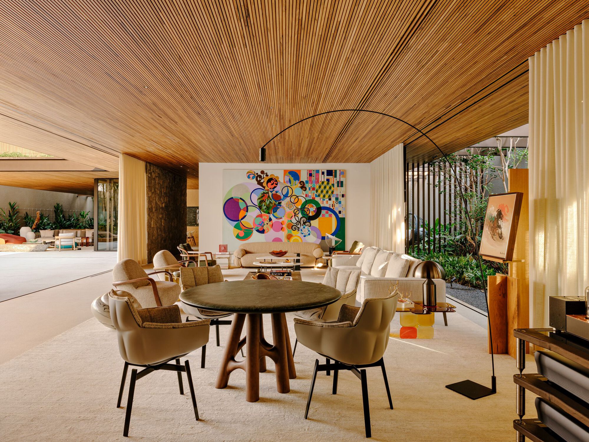 Dining area beneath timber slat ceiling with vertical screen dividing interior courtyard garden