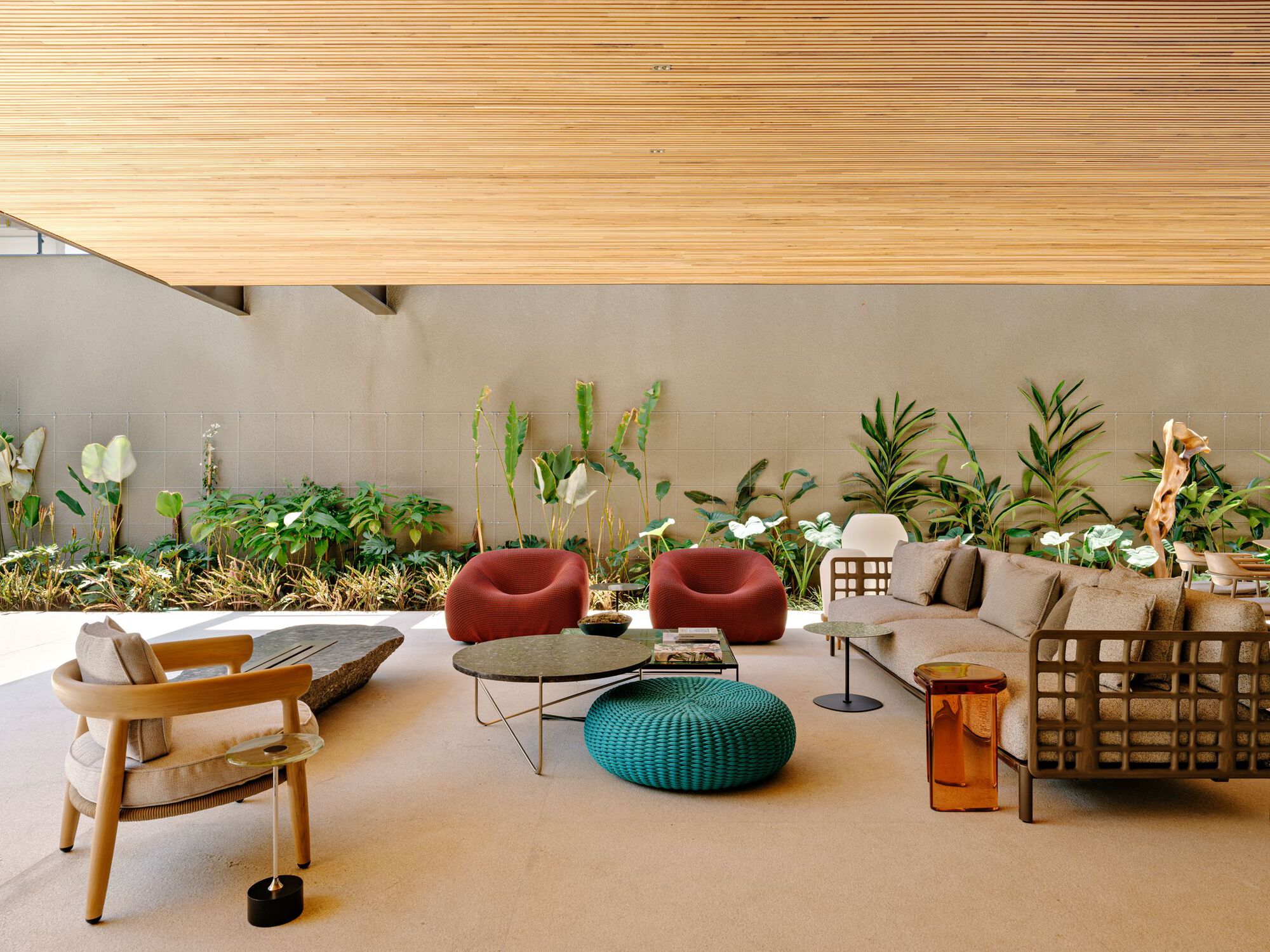Living area with varied seating beneath horizontal timber ceiling and planted bed along the rear wall