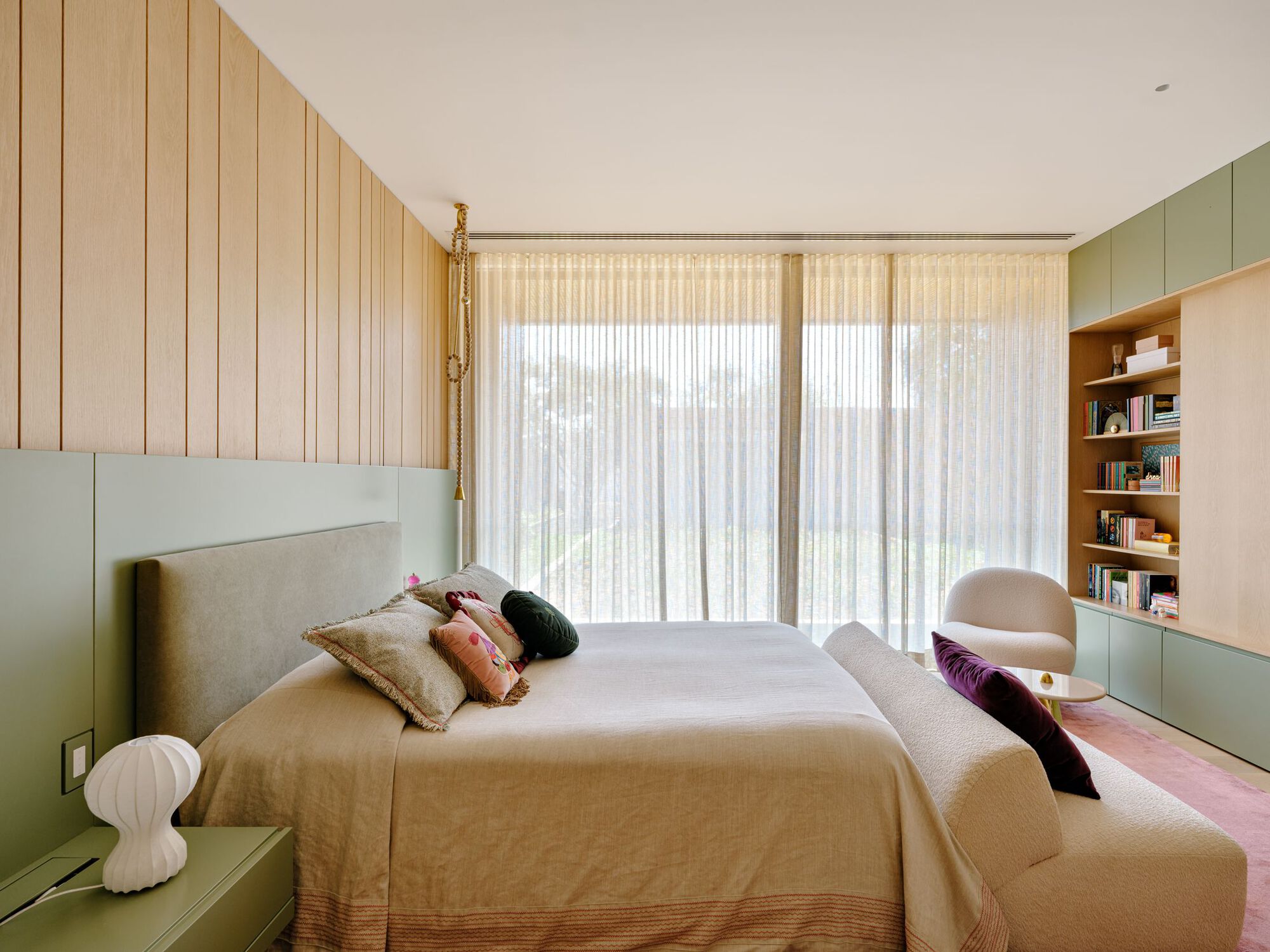 Bedroom with sage-green cabinetry, timber wall battens, and sheer drapes admitting filtered daylight