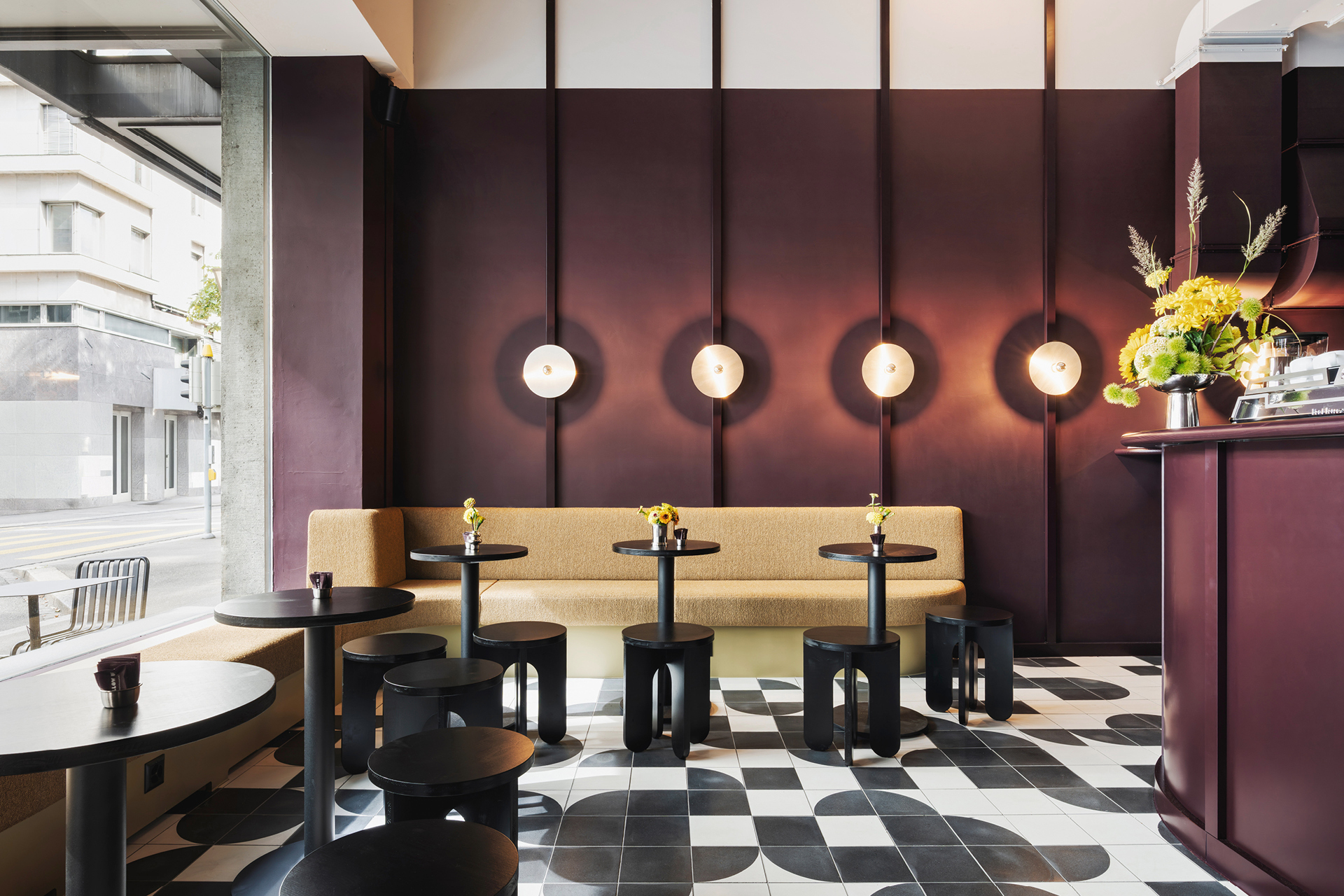 Interior seating area with burgundy paneled wall featuring circular pendant lights and checkered tile floor