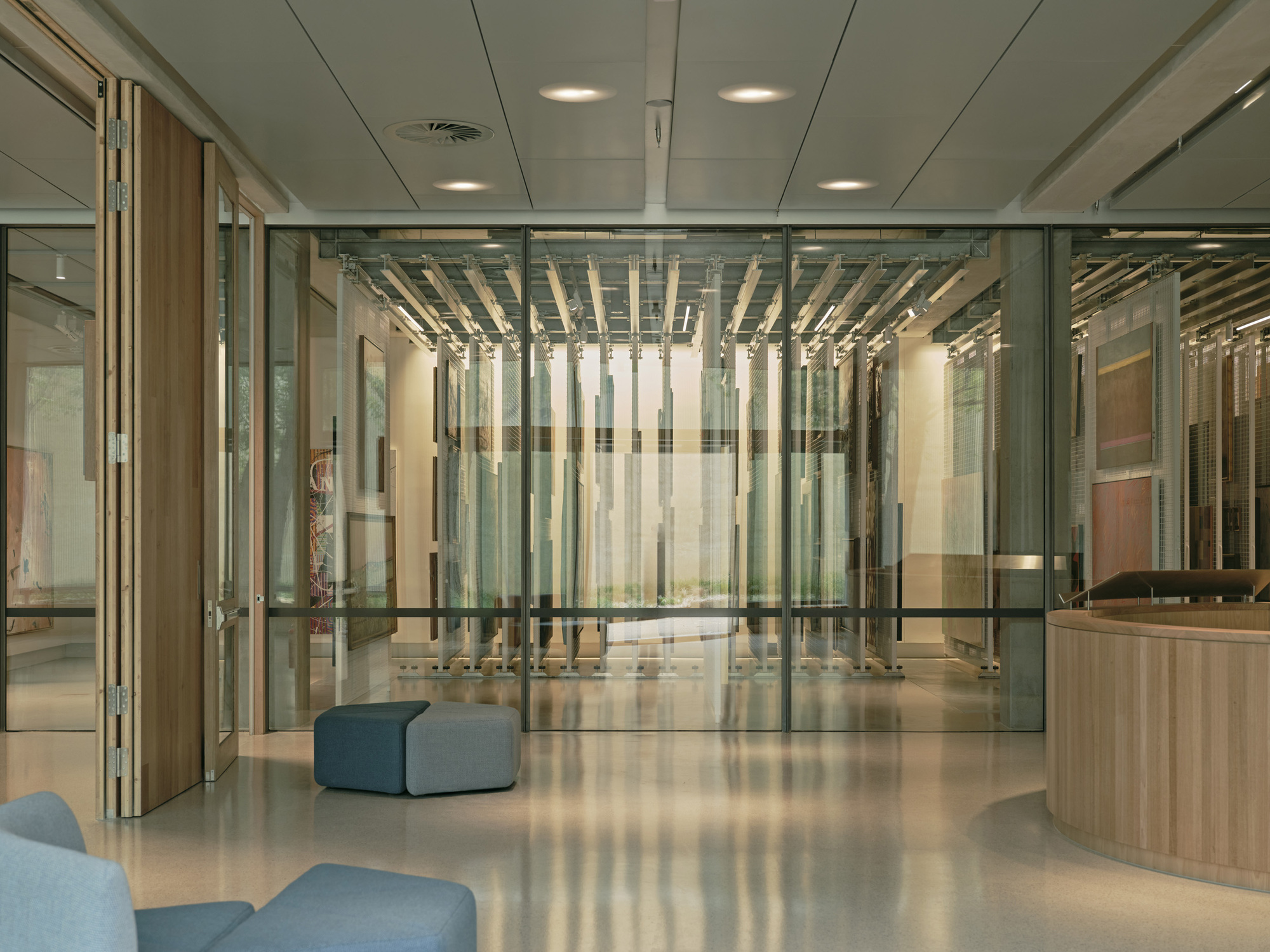 Lobby with glass partitions revealing timber baffle ceiling and polished concrete floor with blue upholstered seating
