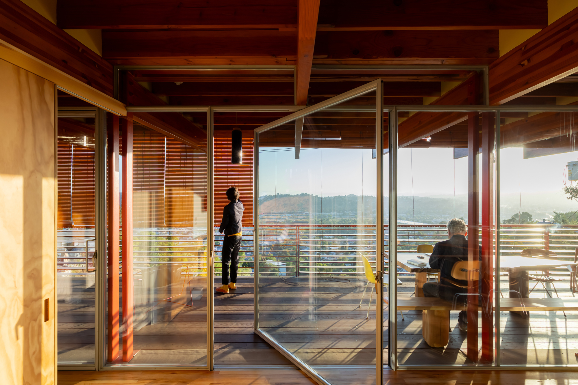 Glass sliding doors opening to terrace with two figures silhouetted against distant hills