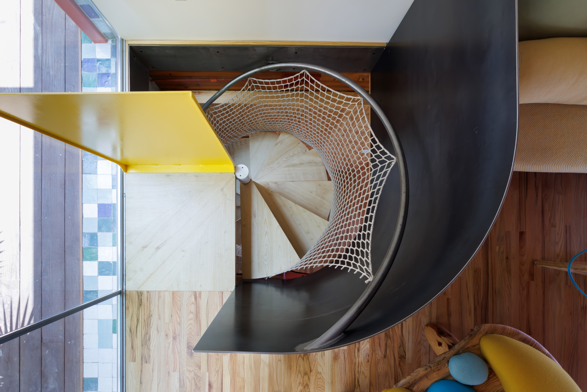 Overhead view of a spiral staircase with rope netting and yellow steel handrail