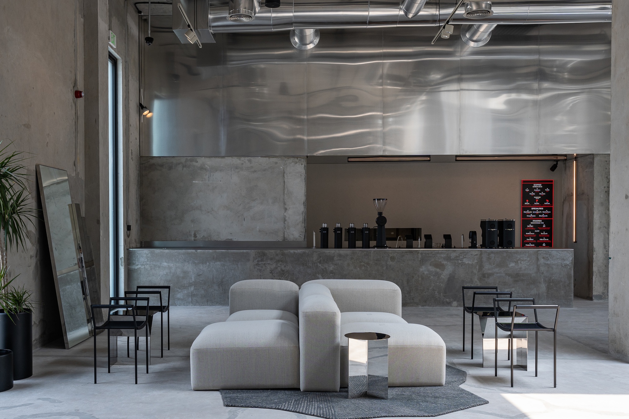 Reception area with concrete service counter and exposed ceiling ducts beneath reflective metal panels