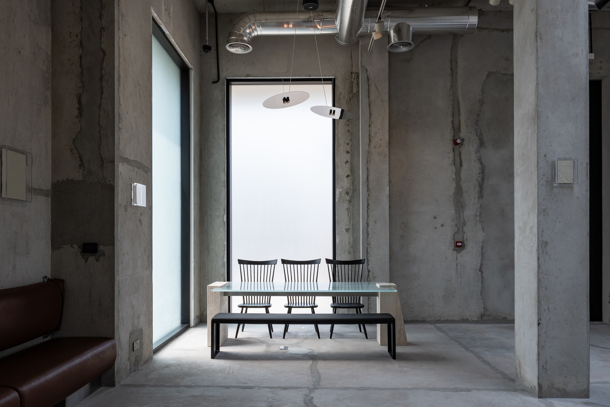 Marble table with metal chairs beneath a pendant light and tall window
