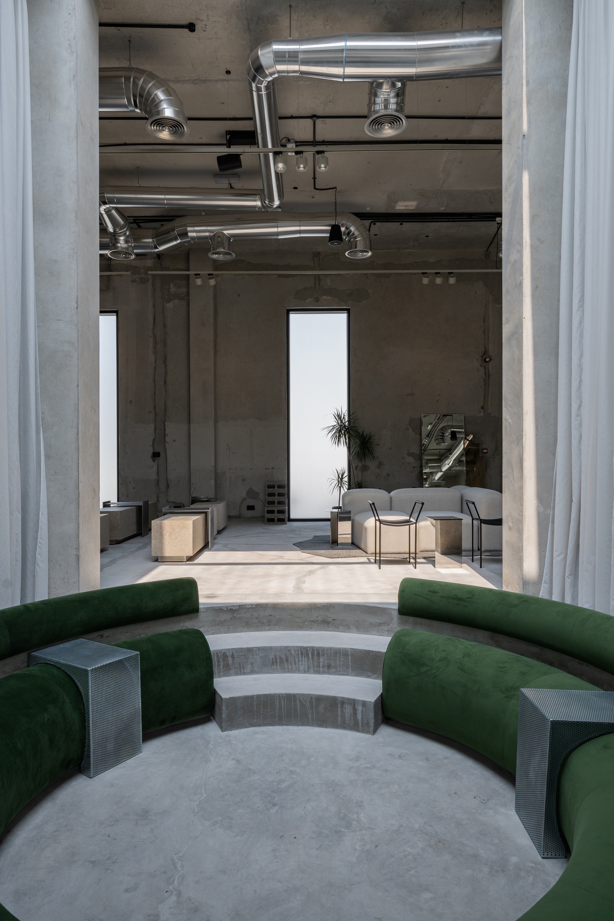View through curtained opening toward circular stepped seating with green cushions