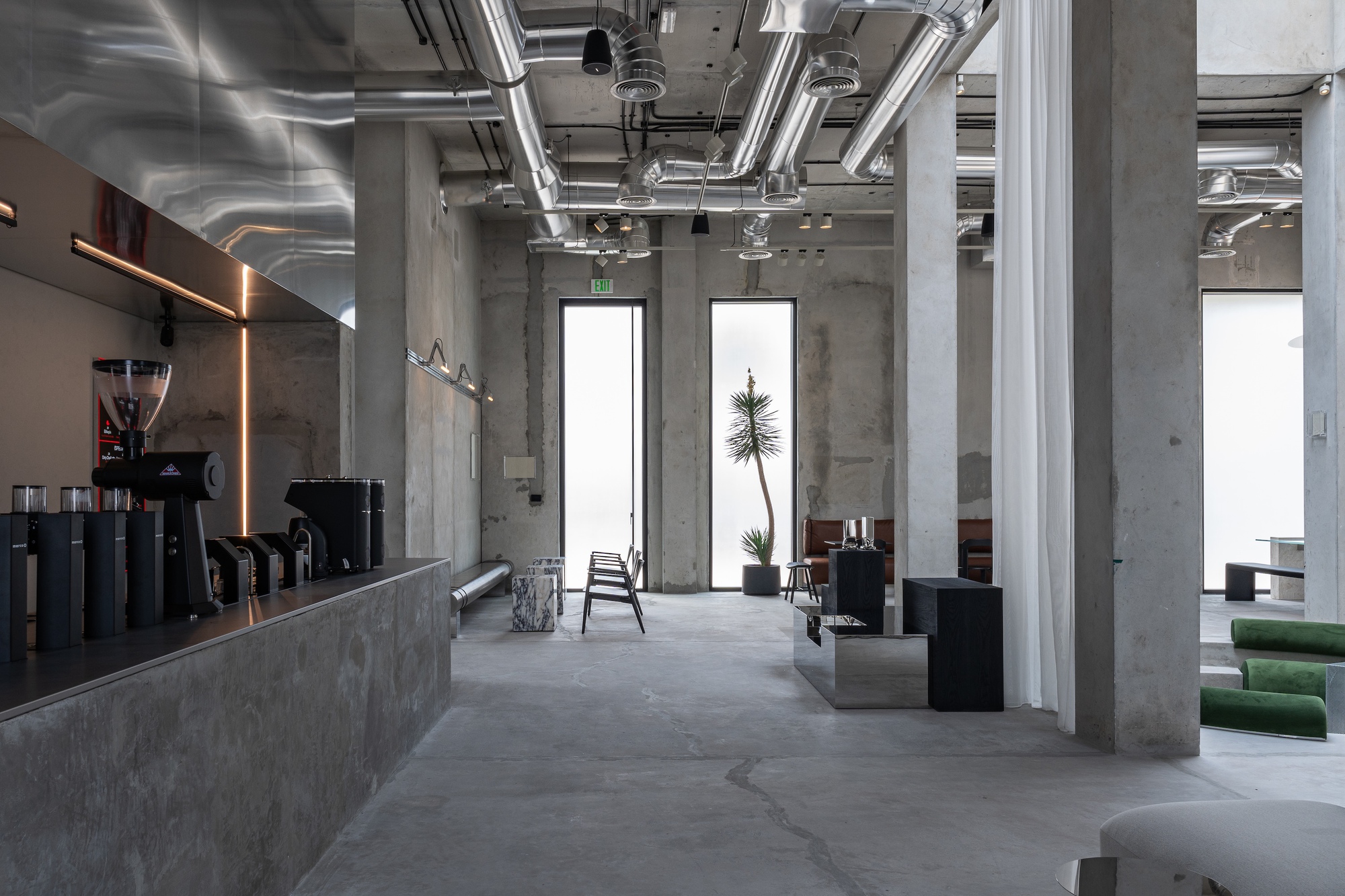 Open seating area with exposed mechanical systems overhead and concrete columns defining the space