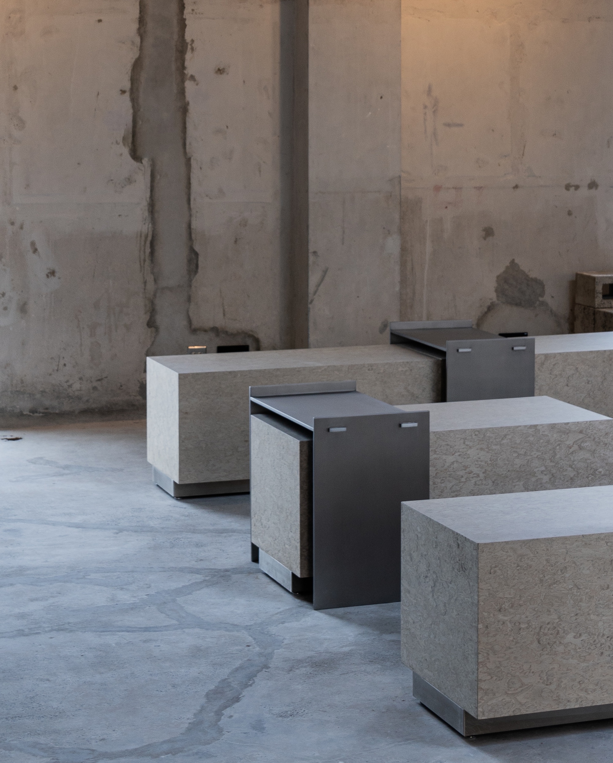 Concrete block seating units with blackened steel pull-out seats on a polished floor