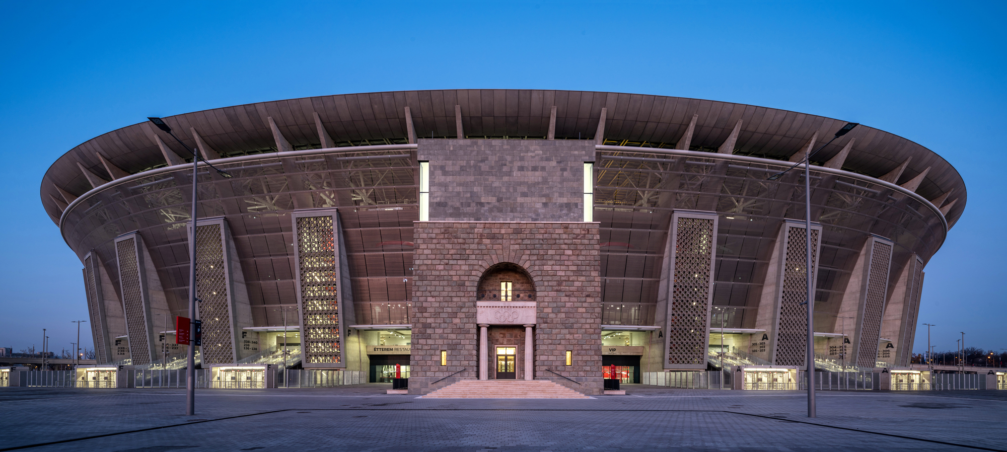Arched entrance portal flanked by latticed towers and horizontal glazing at twilight