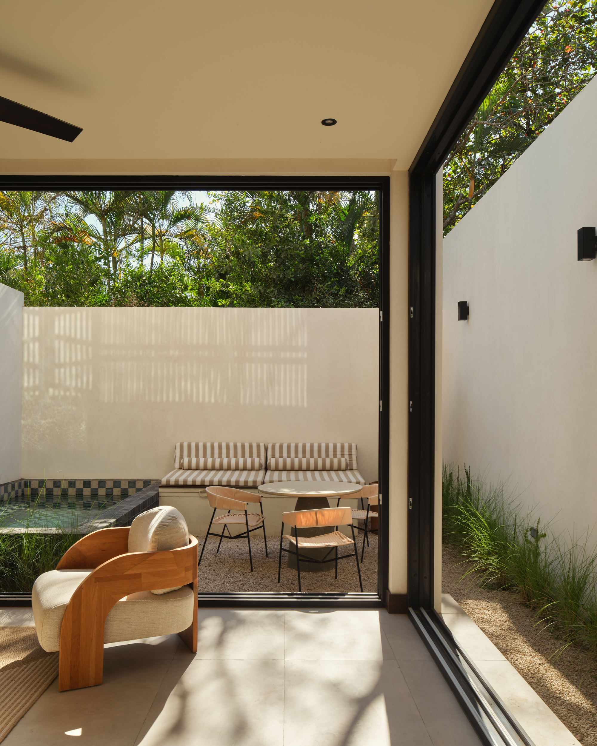 Interior view through sliding glass doors to a private courtyard with tiled water feature and seating