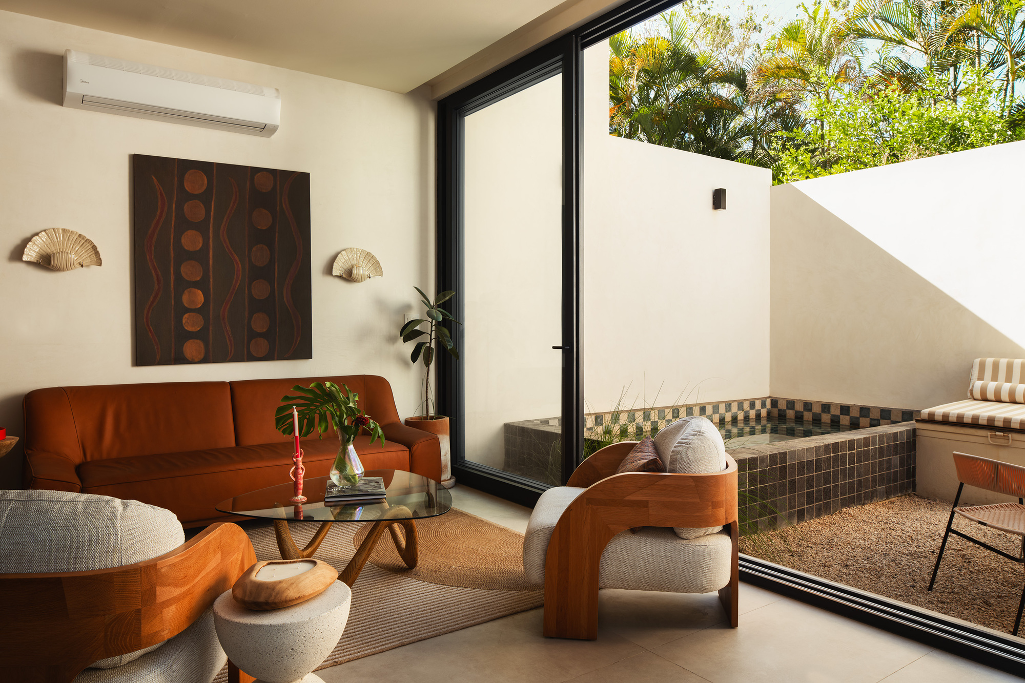 Living room opening to a tiled courtyard terrace through a sliding glass door in afternoon light