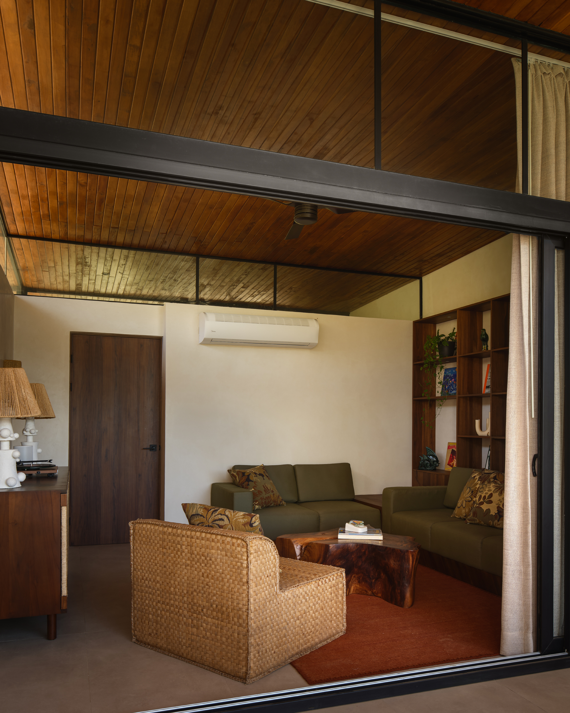 Living room with timber slat ceiling, mezzanine above and terracotta floor tiles