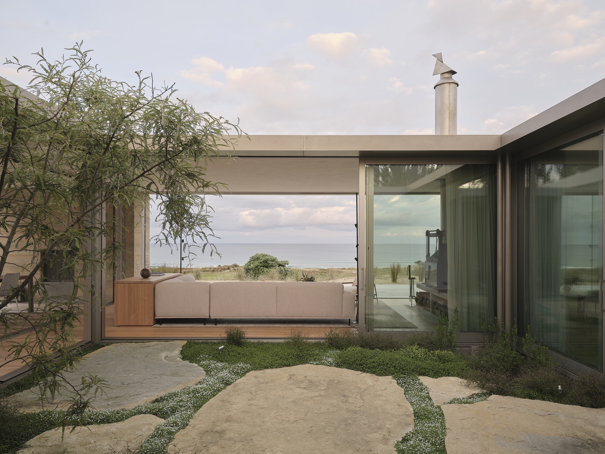 Internal courtyard with limestone pavers and planted groundcover framed by glass walls and concrete beams