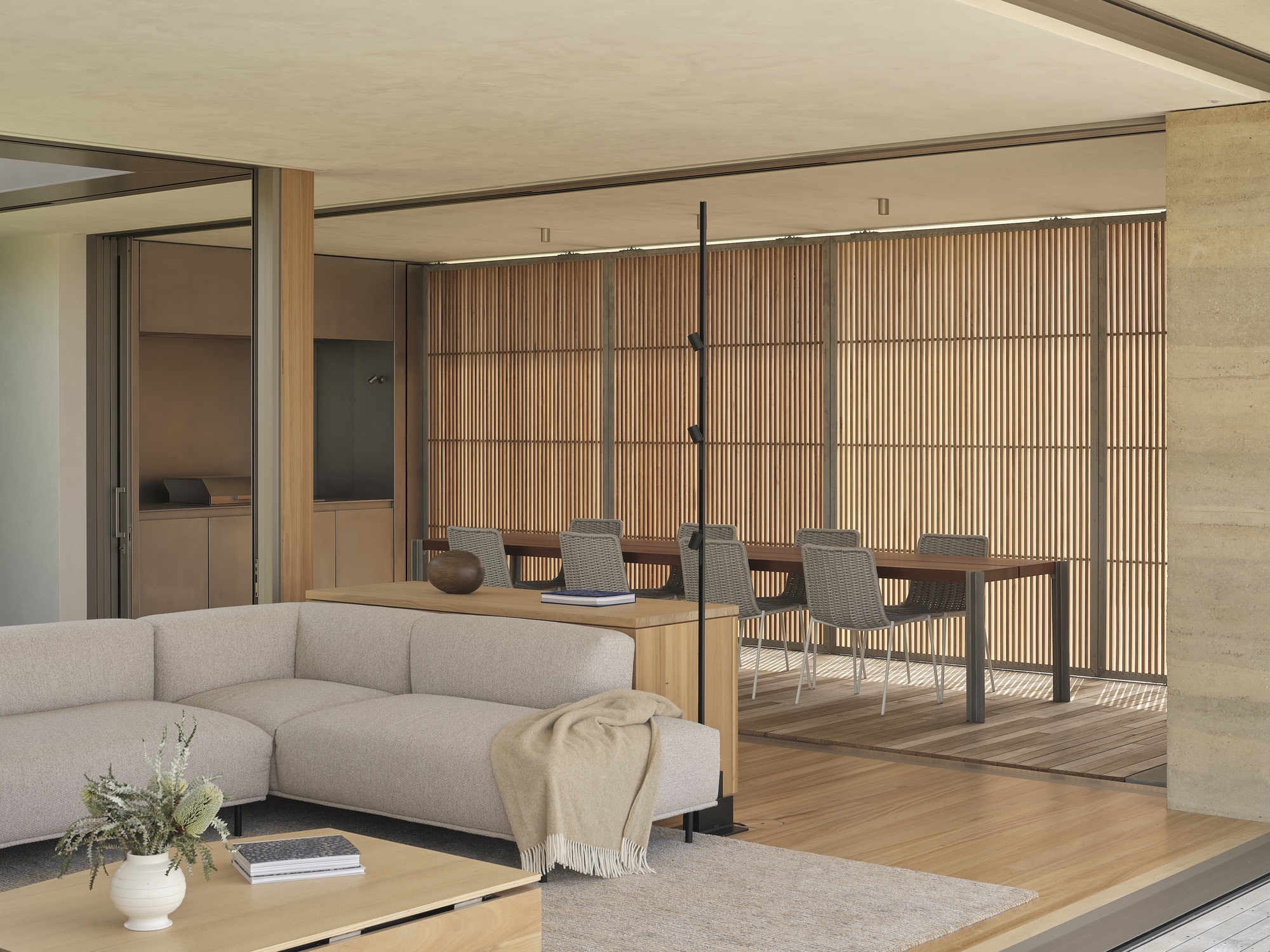 Living space opening to outdoor dining terrace with slatted timber screen and suspended black pendant light