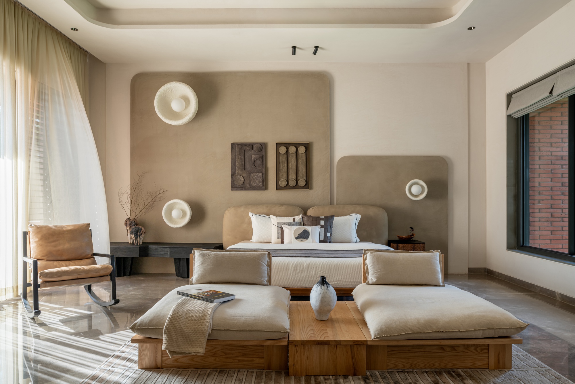 Bedroom with rounded plaster wall niches and circular sconces above upholstered headboard