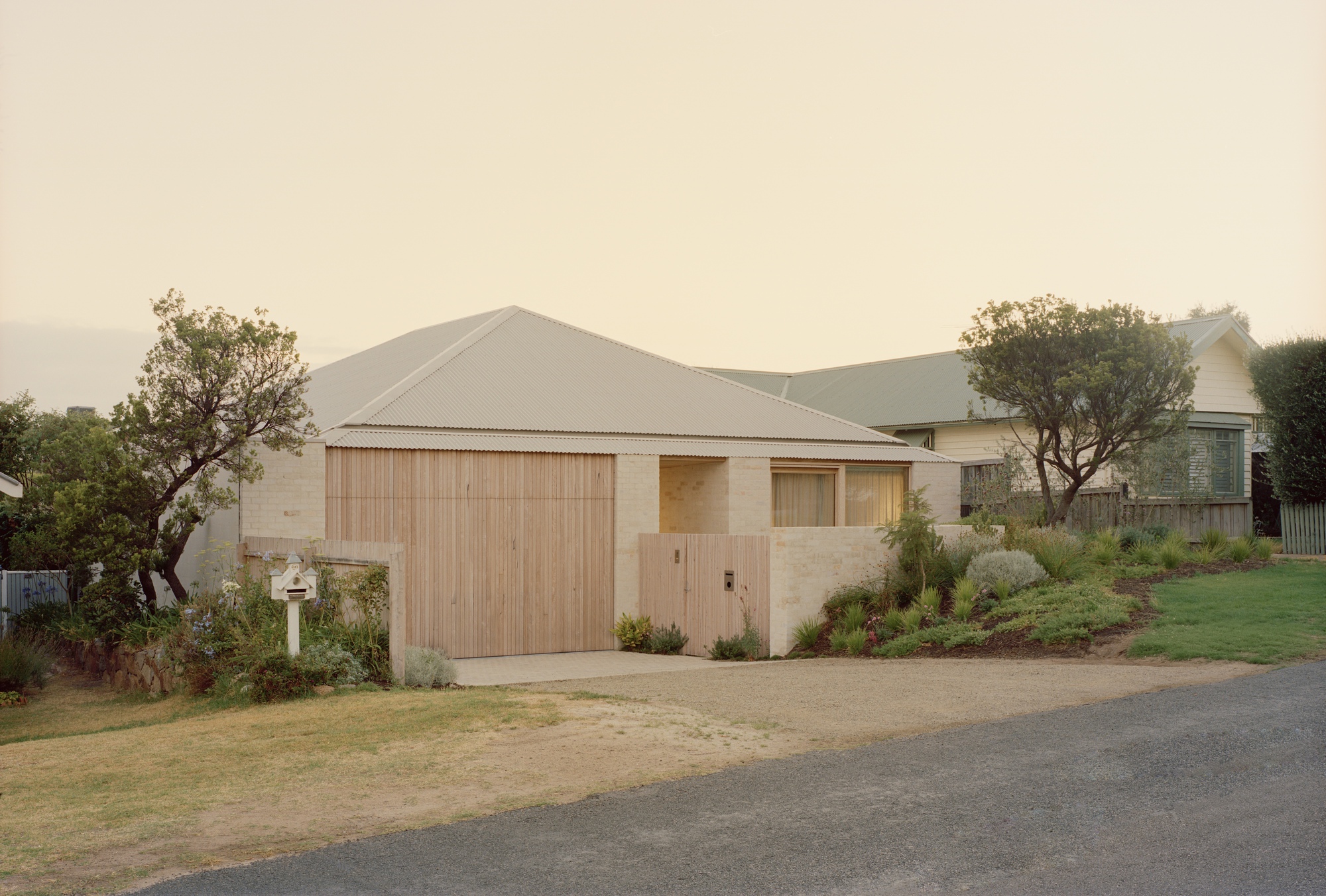 Street view of the sandstone and timber facade with gabled corrugated metal roof under hazy skies