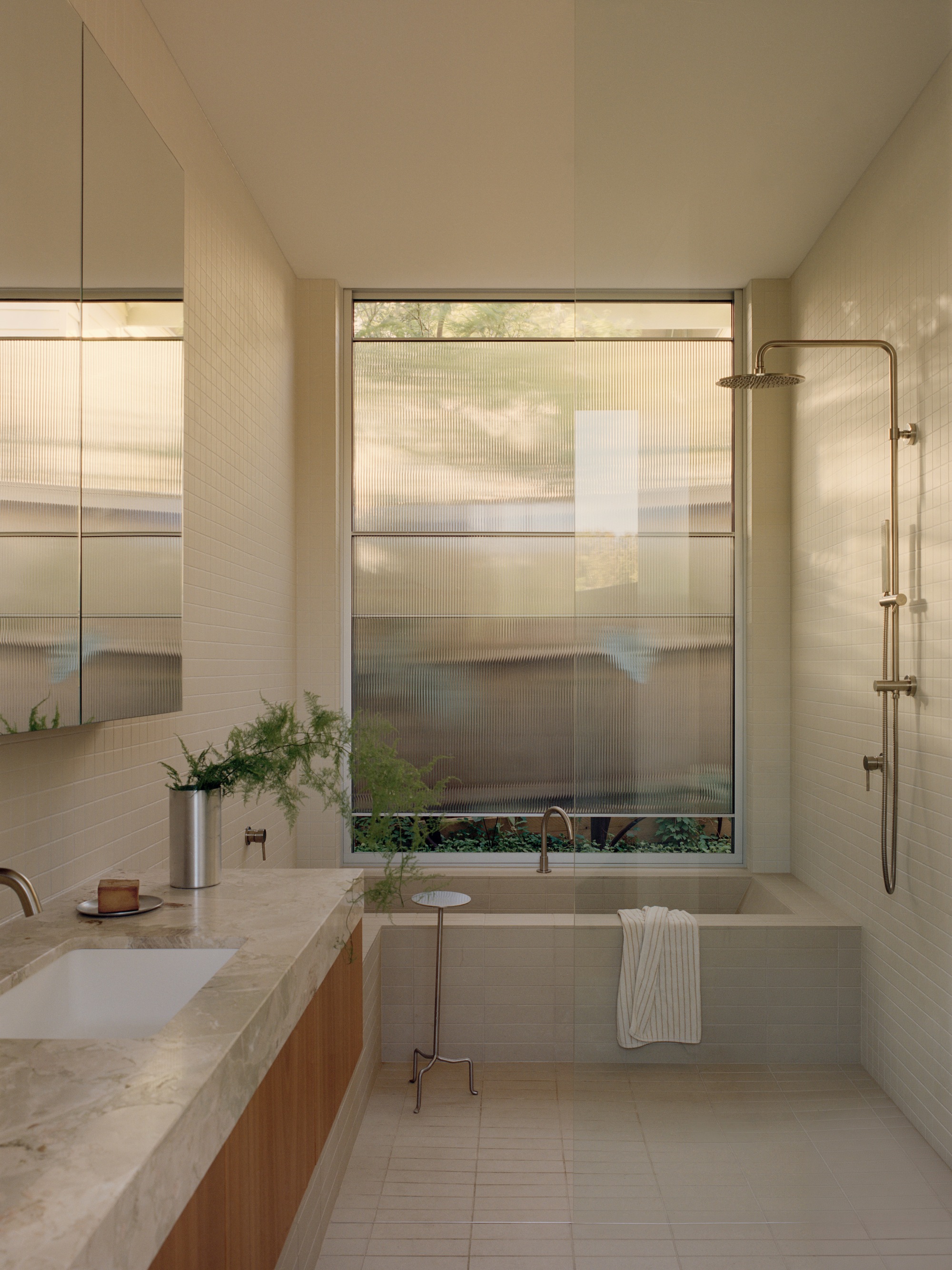 Bathroom with terrazzo vanity and translucent window shades filtering afternoon light
