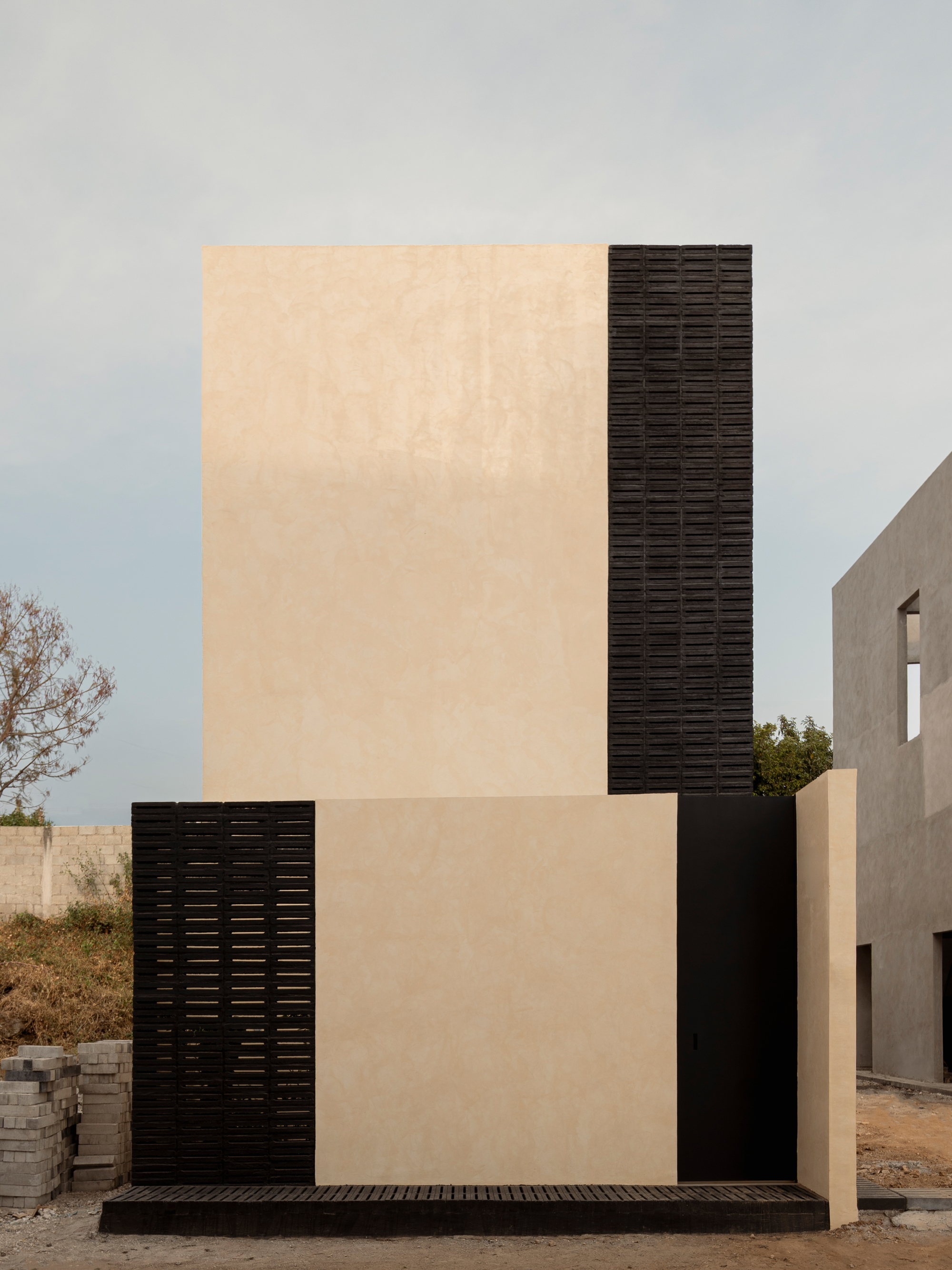 Street-facing elevation showing cream plaster wall contrasting with vertical bands of dark textured brick