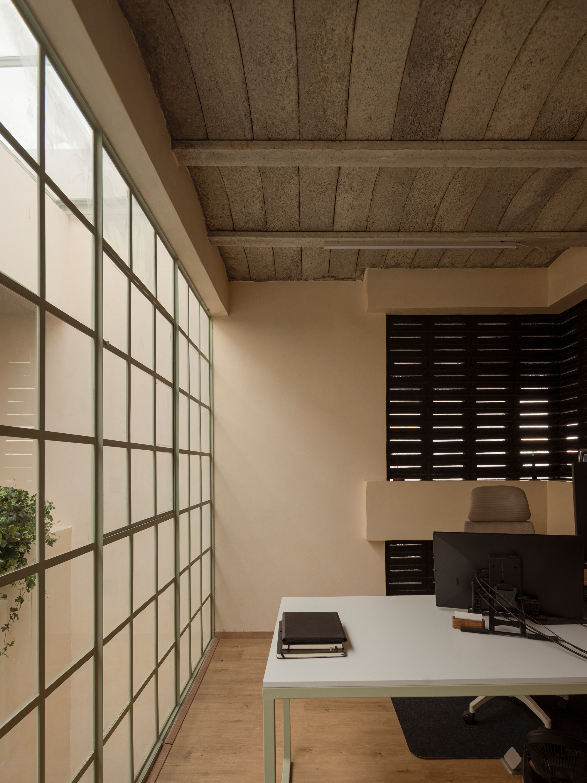 Workspace with translucent gridded glass wall, exposed timber ceiling beams and horizontal louvered screen