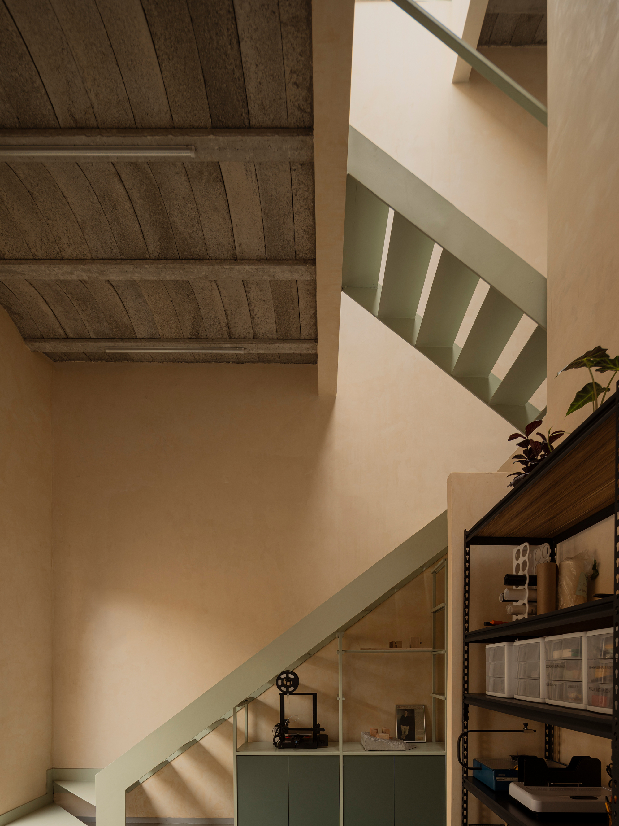 Stairwell with pale green handrail and storage shelving beneath the timber-beamed ceiling