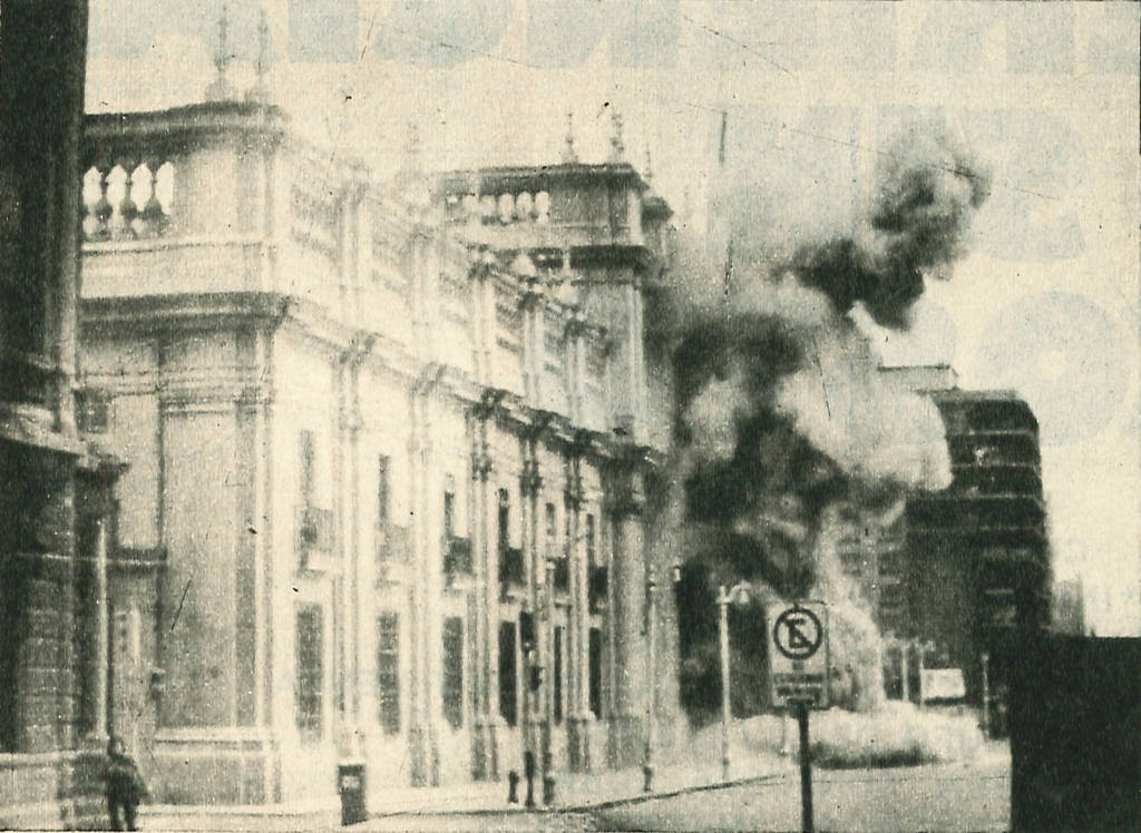 Archival photograph showing a white neoclassical facade with balustrades and columns amid dark smoke