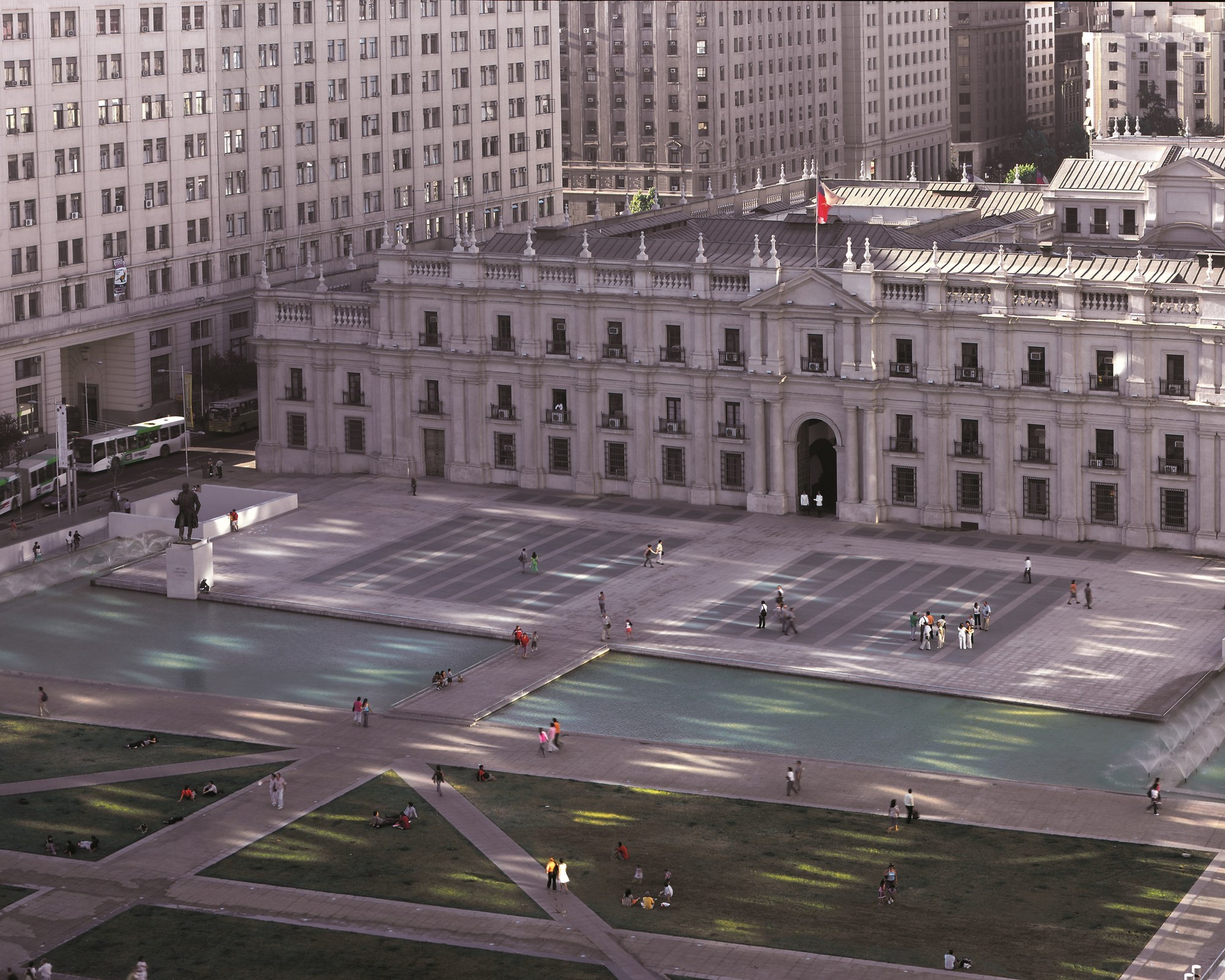 Aerial view of the paved plaza with triangular water features and people gathered below