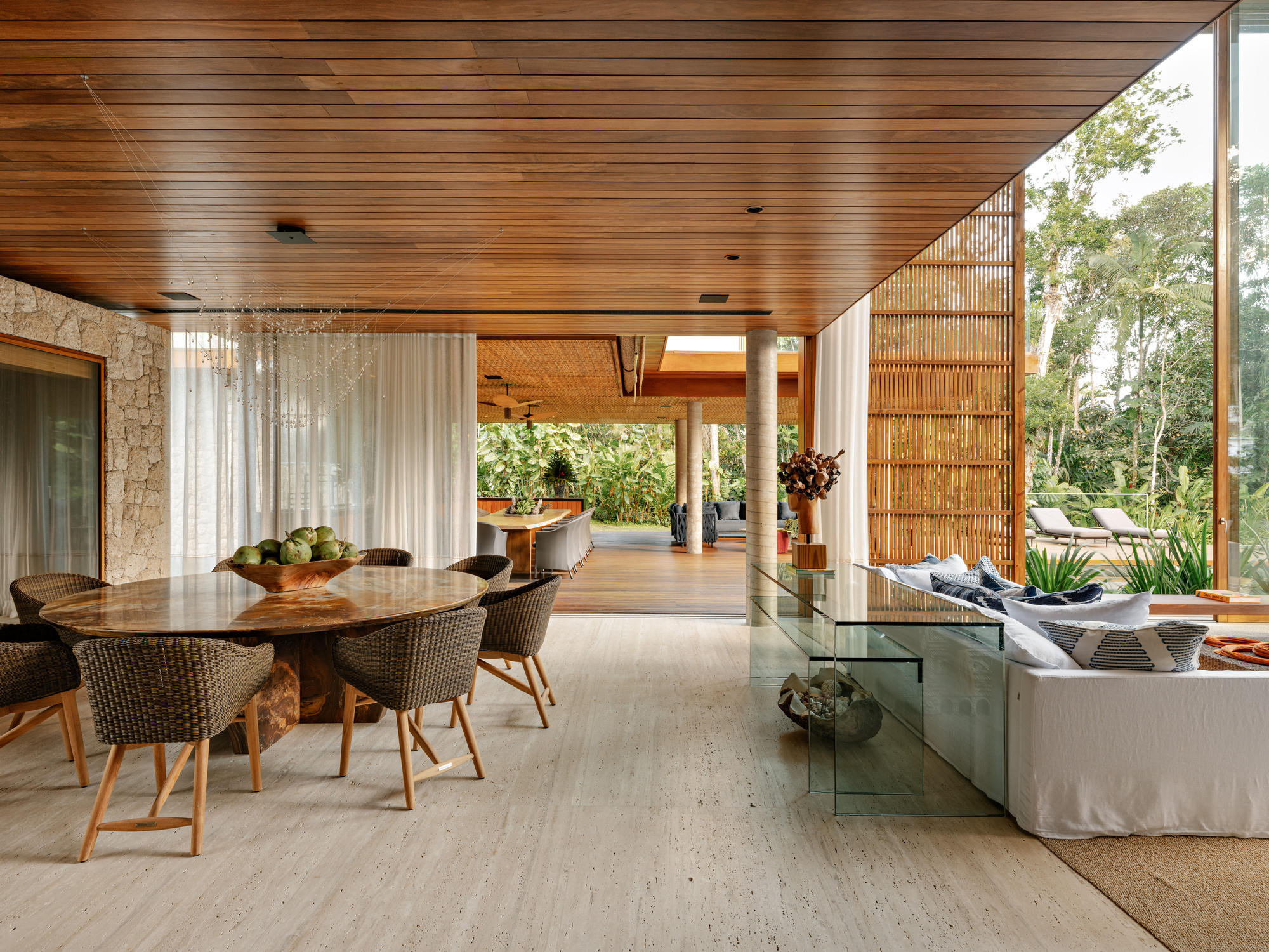 Open-plan dining and living space under timber ceiling with slatted screen dividing interior from terrace