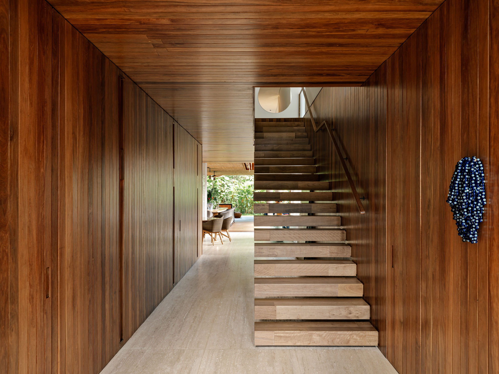 Timber-lined corridor with open treads staircase ascending to a skylight above