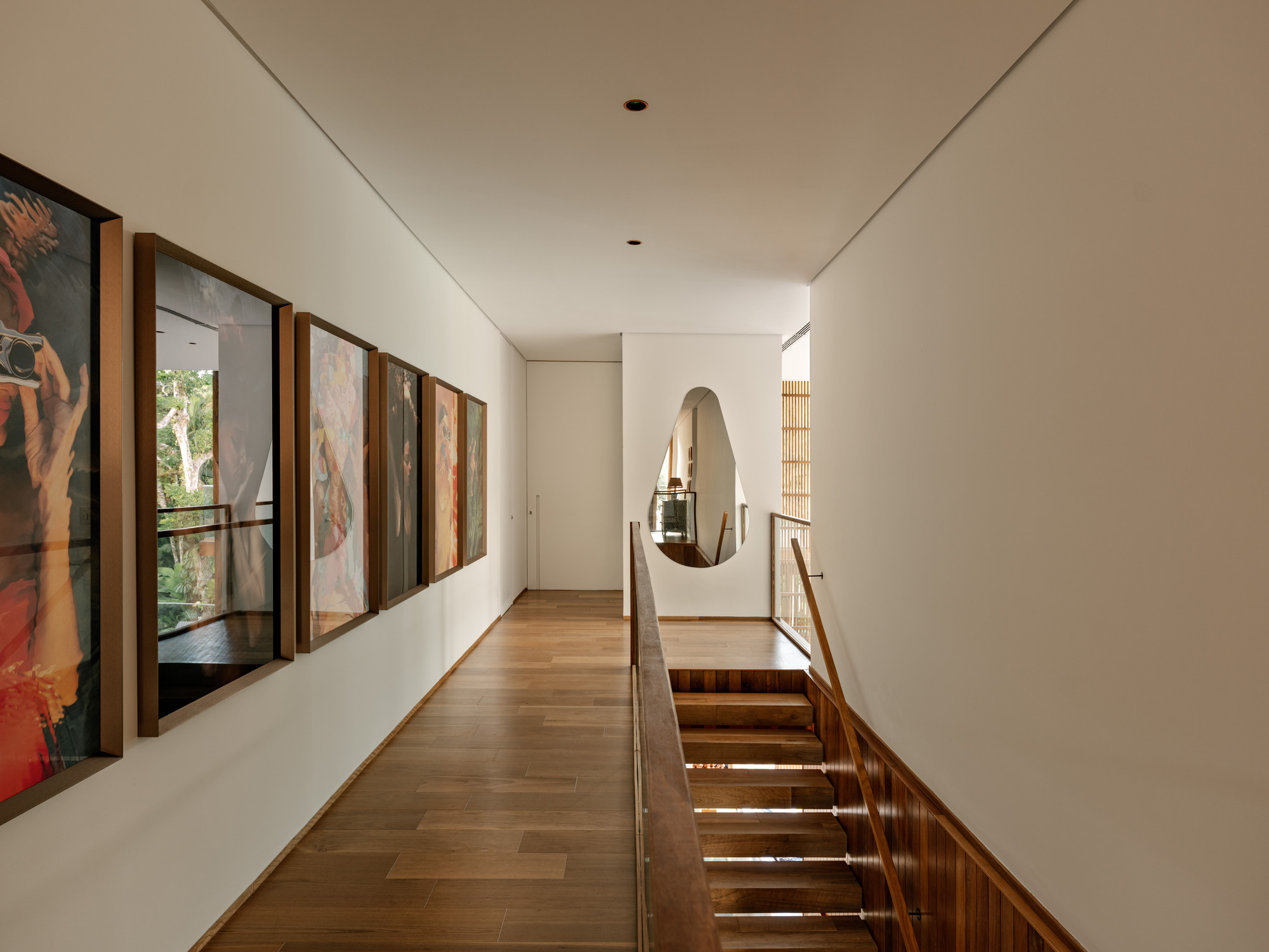 Upper-level hallway with teardrop aperture overlooking stairwell and timber-framed windows