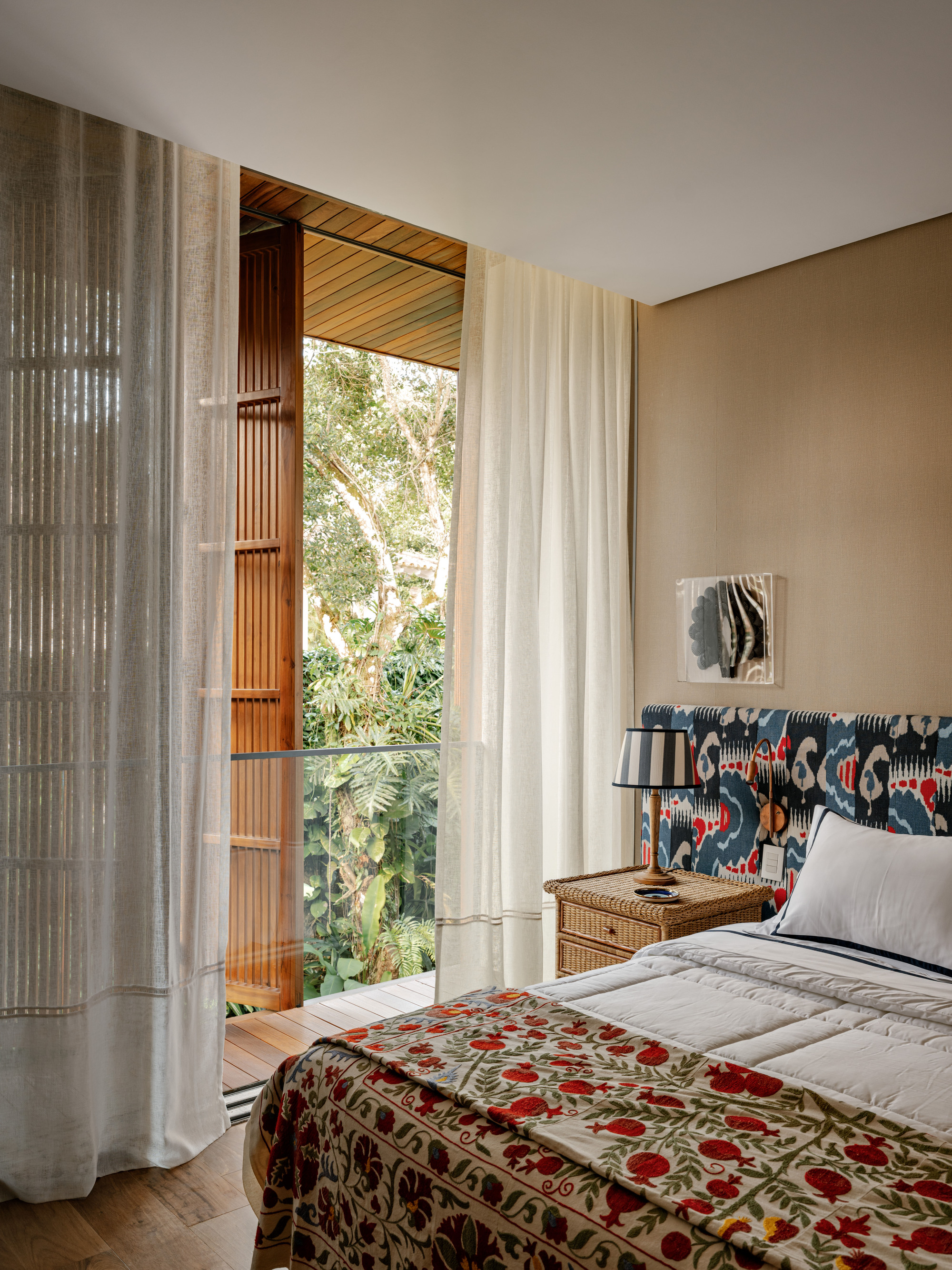 Bedroom with view through timber-lined opening to balcony and trees in daylight