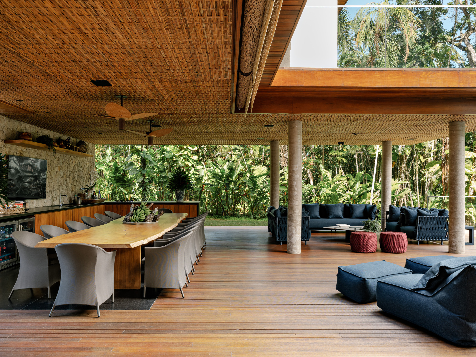 Open-air pavilion with woven bamboo ceiling, timber columns, and teak decking surrounded by tropical vegetation