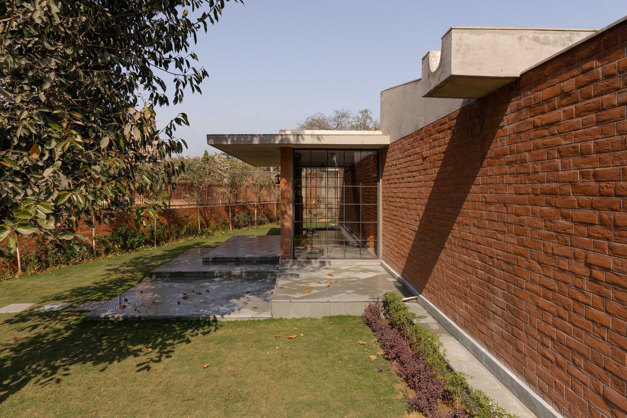 Exterior view of angled brick wall and glazed entry pavilion adjacent to a shallow reflecting pool