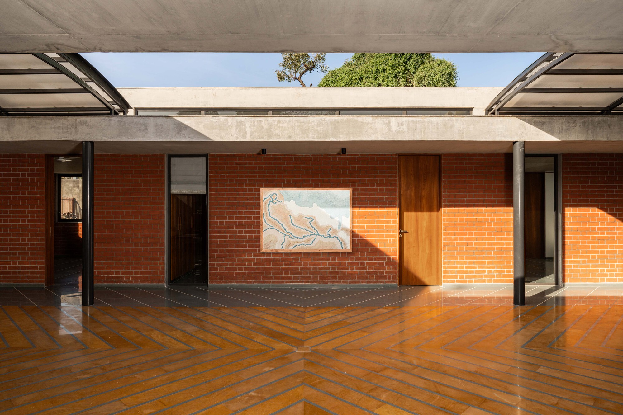Covered terrace with herringbone brick paving, timber door, and artwork illuminated by late afternoon sun