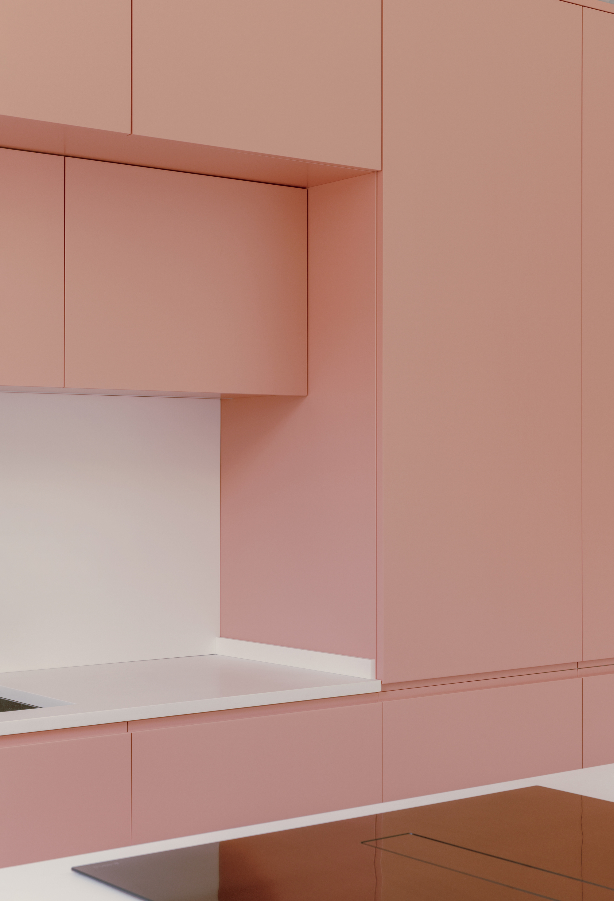 Close-up of pink cabinet joinery meeting white countertop with recessed overhead cabinet detail