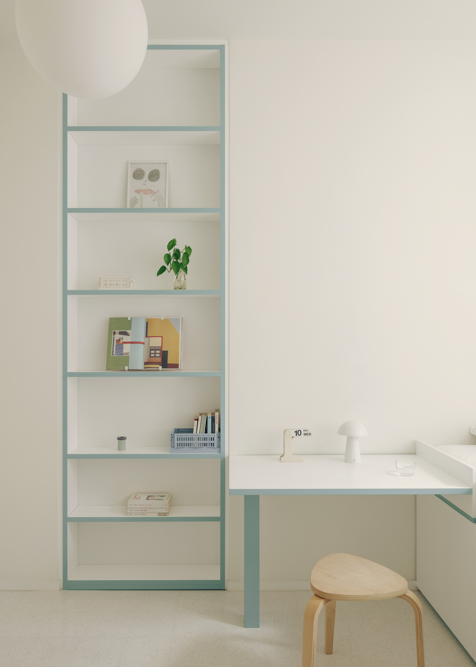 Pale blue steel shelving and desk unit with bentwood stool in soft natural light