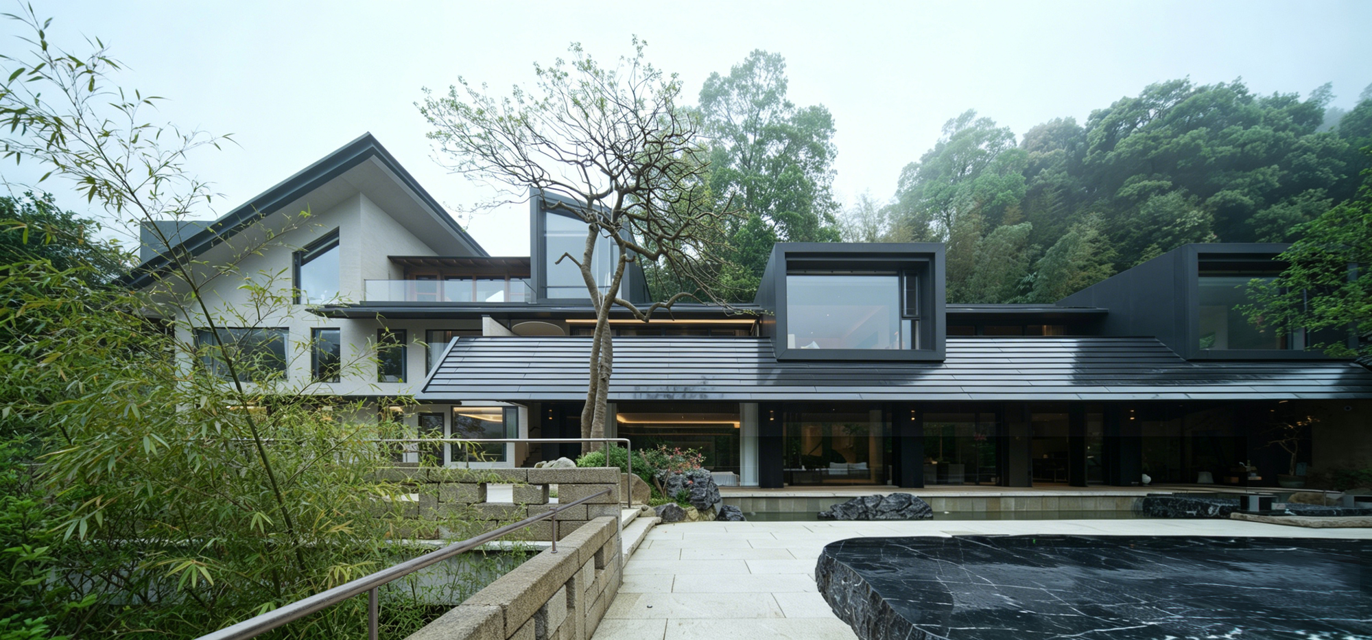 Stone terrace and circular pool beside a house with corrugated metal roofing beneath dense green forest
