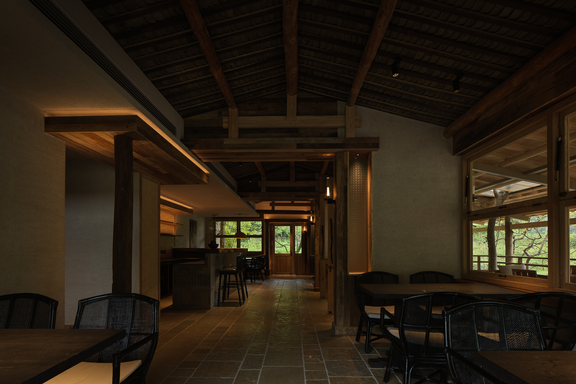 Interior dining hall with exposed timber ceiling beams and stone floor tile