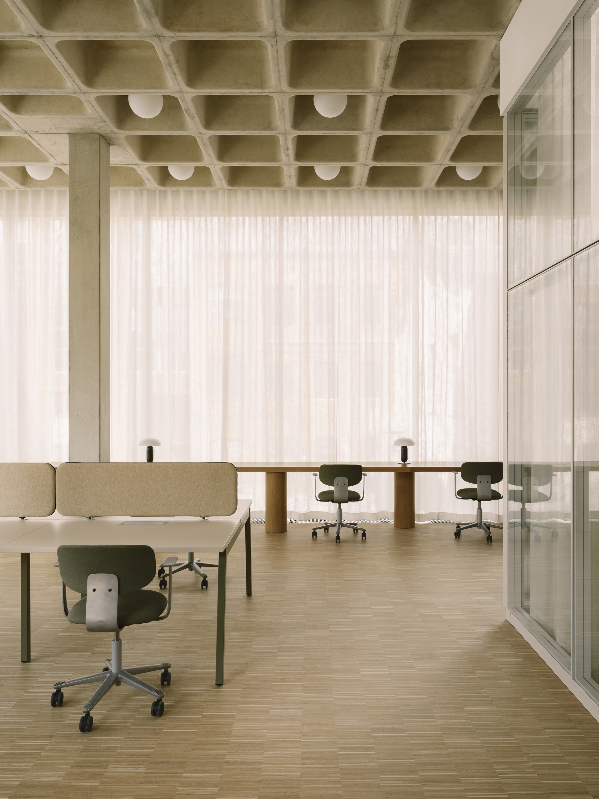 Open office space with waffle slab concrete ceiling, spherical pendant lights, and sheer curtains filtering daylight