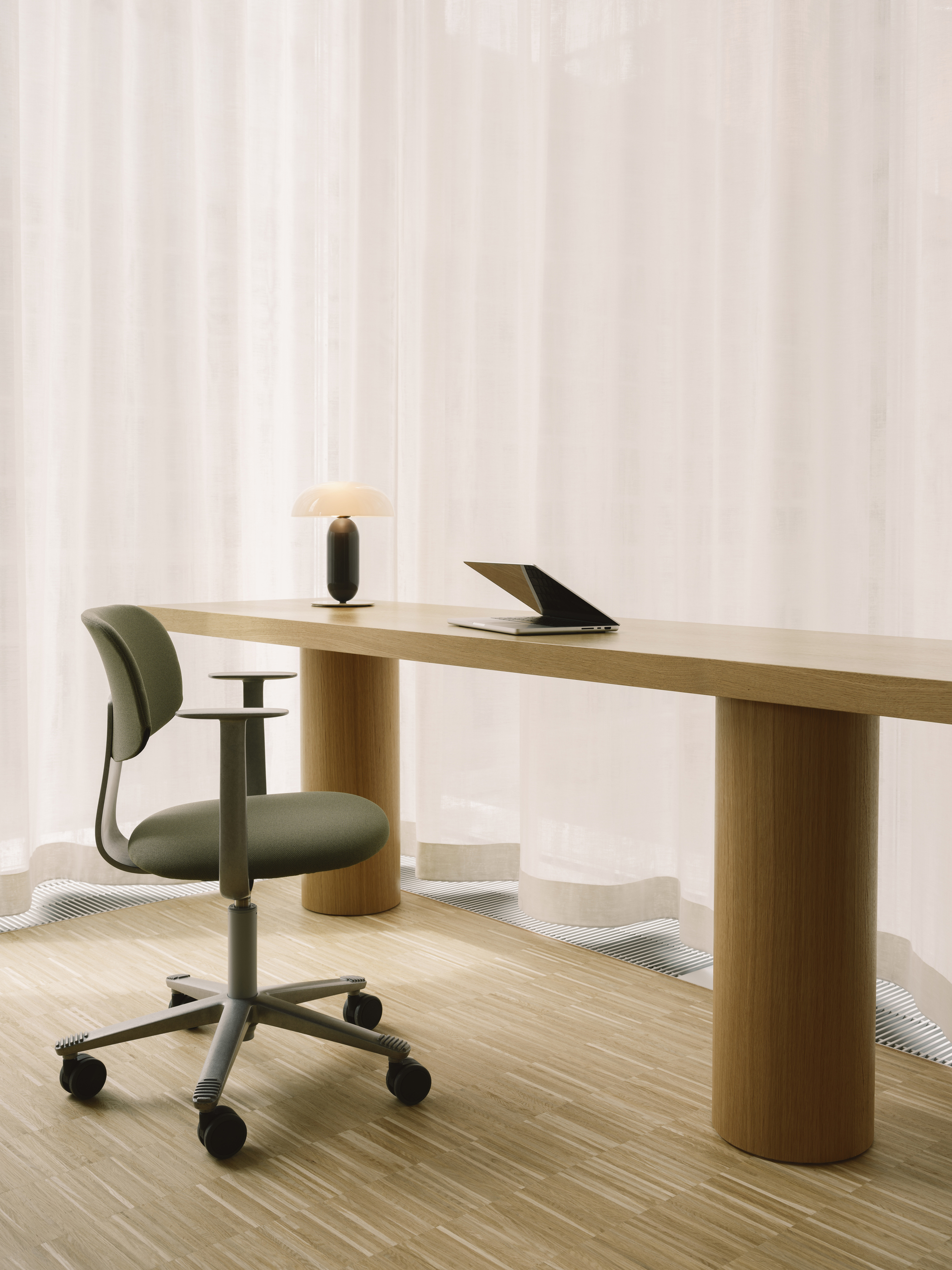 Workspace with cylindrical wood desk legs and upholstered task chair on light oak flooring