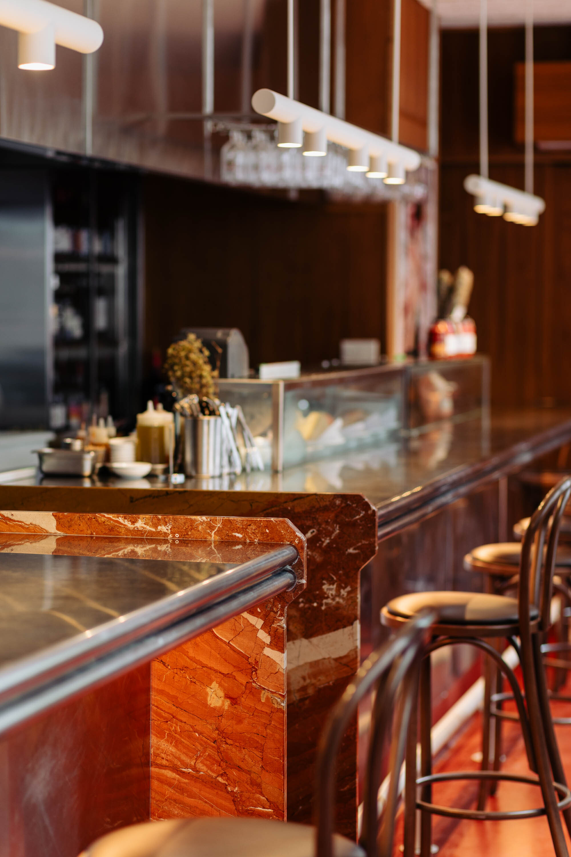 Detail of red veined marble counter end with rounded steel edging in soft focus