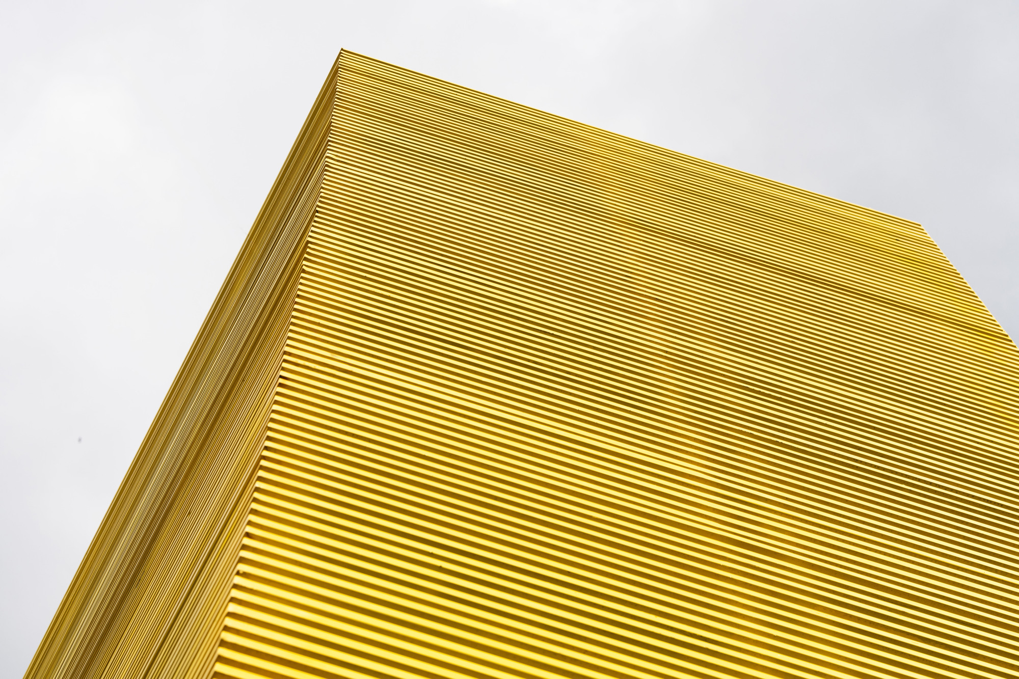 Close-up of the yellow corrugated metal facade corner against an overcast sky