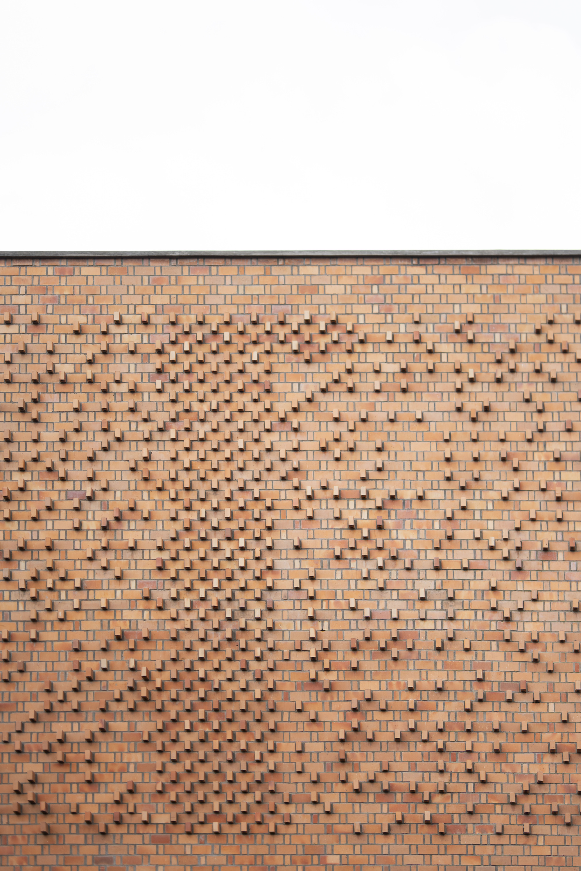 Patterned brick facade with projecting and recessed bricks forming a diamond motif
