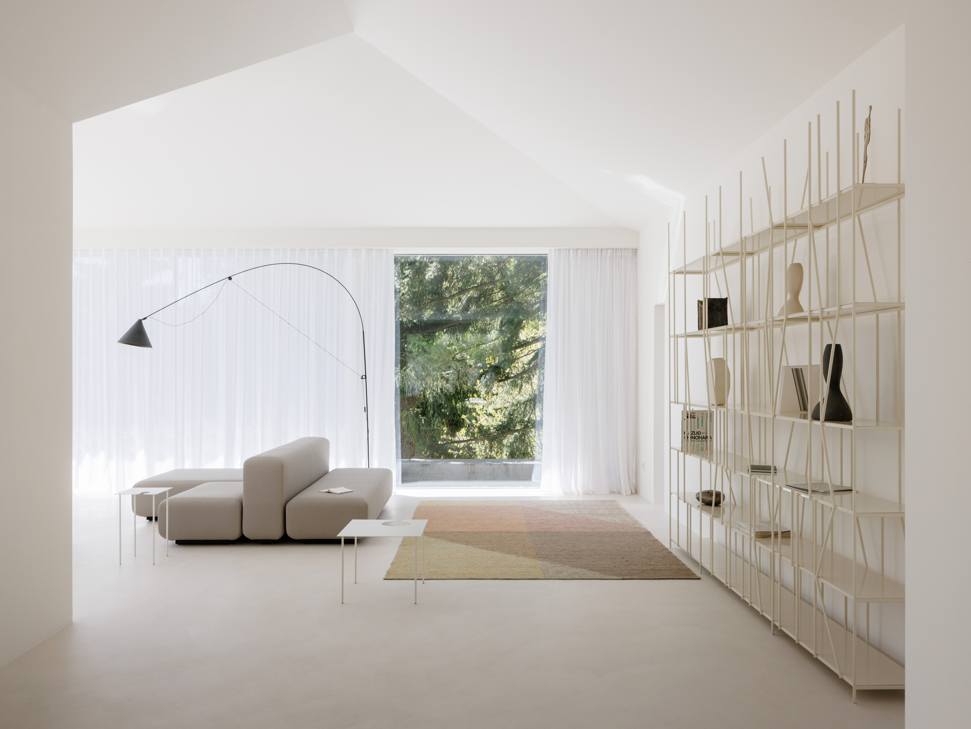 White interior with arched ceiling, brass shelving unit, and full-height curtains framing garden views